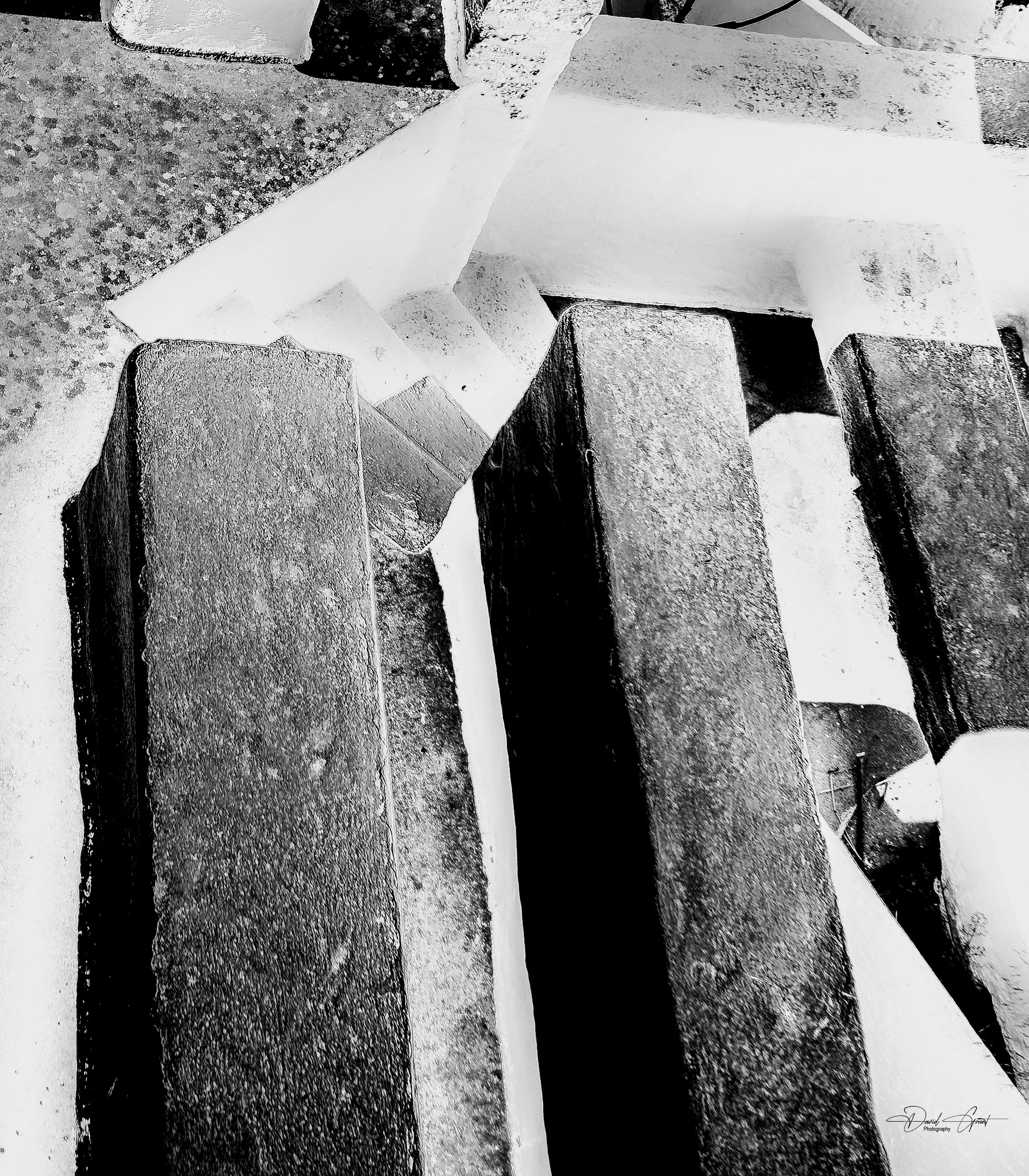 Close-up photograph of large, rectangular stone blocks with textured surfaces, arranged in an abstract composition with contrasting light and shadows.