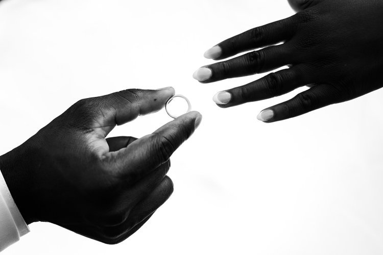 Two hands, one with a wedding ring, reaching towards each other against a backlit background in Dayton Ohio.