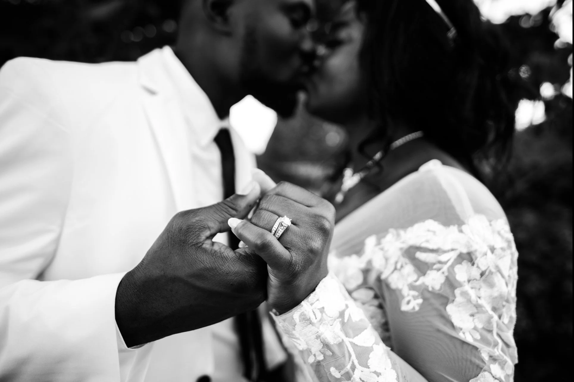 A Black groom and a bride are holding hands in Dayton Ohio, touching each other's fingers, with a wedding ring visible on the brides's finger.