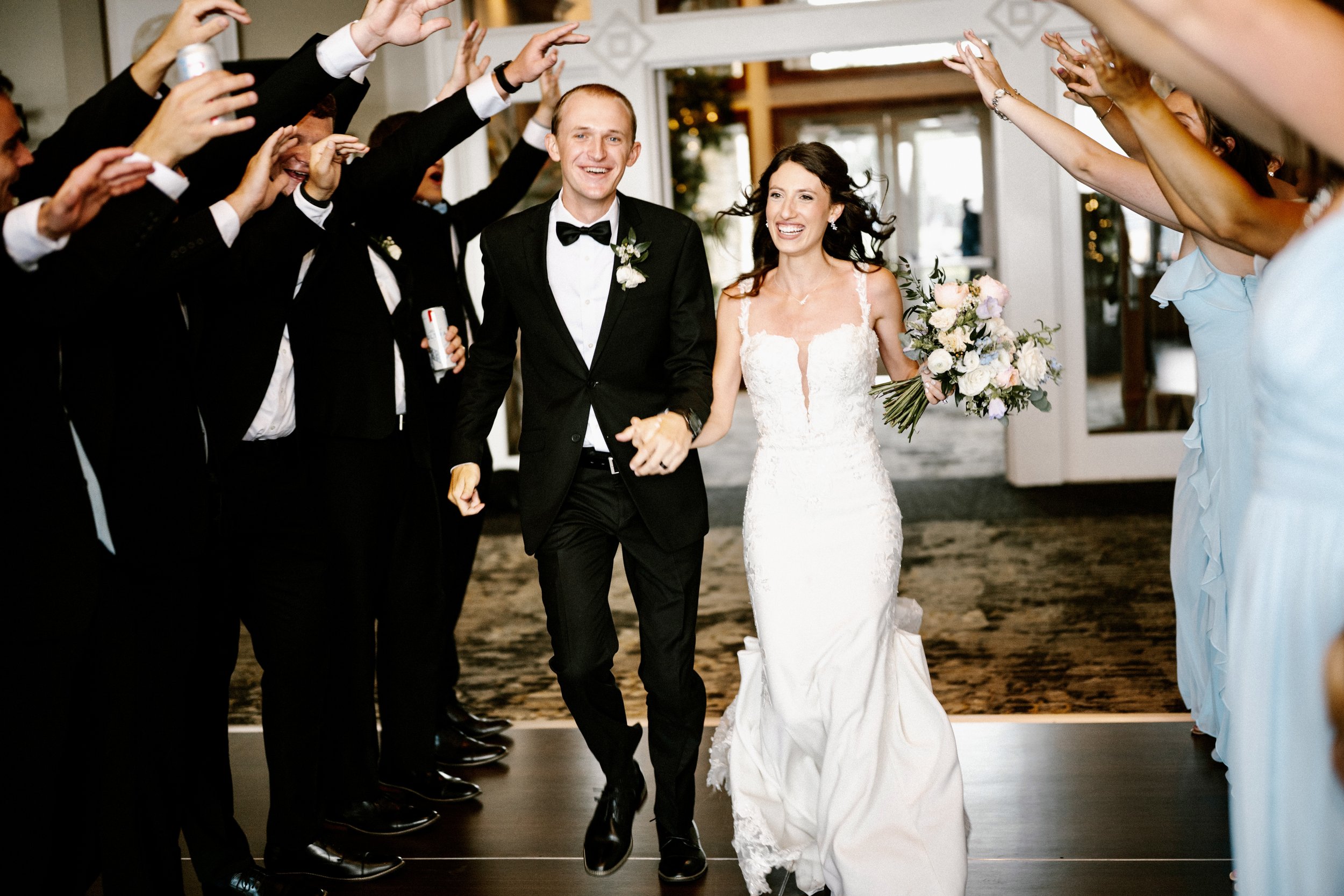 A Cincinnati Ohio newlywed couple walking down the aisle, surrounded by friends and family celebrating at a wedding reception.