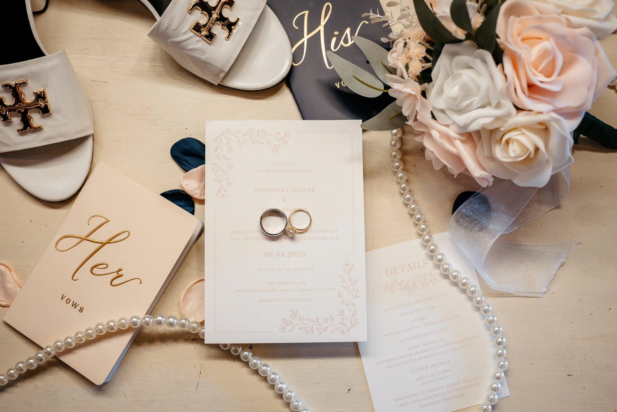 A Cincinnati Ohio wedding flat lay with rings, flowers and invitations.