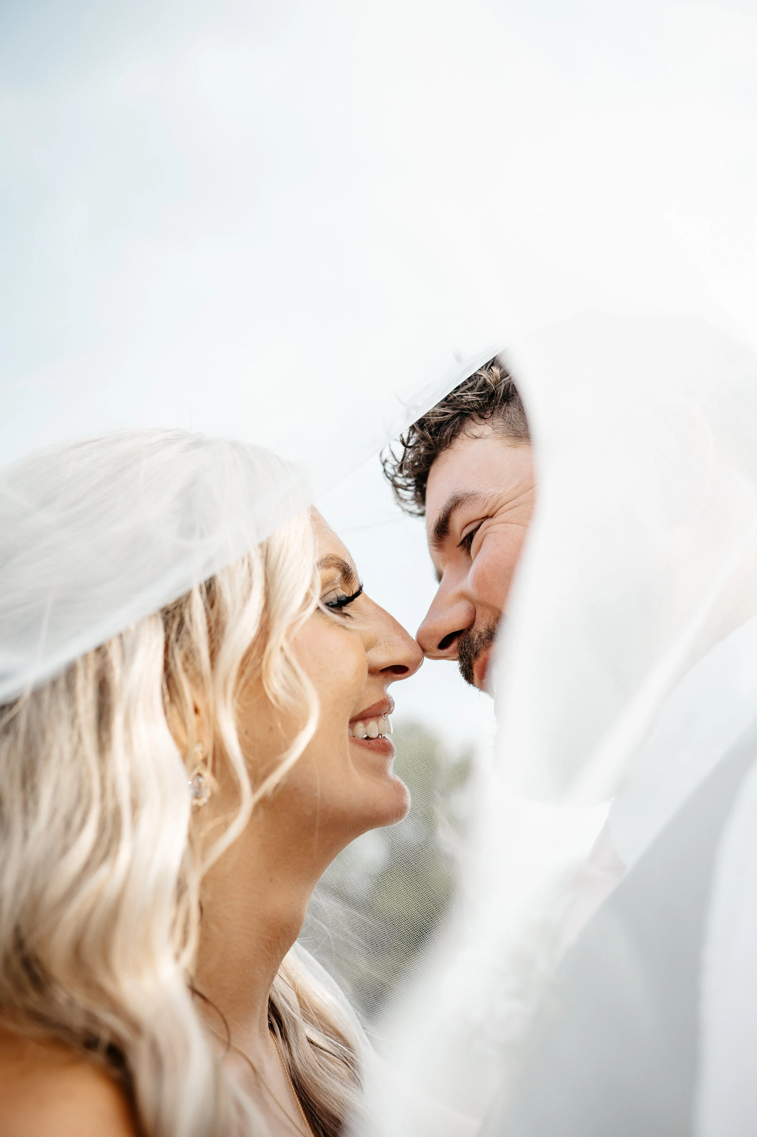 A Cincinnati bride and groom smiling under the brides veil during the couples portraits.