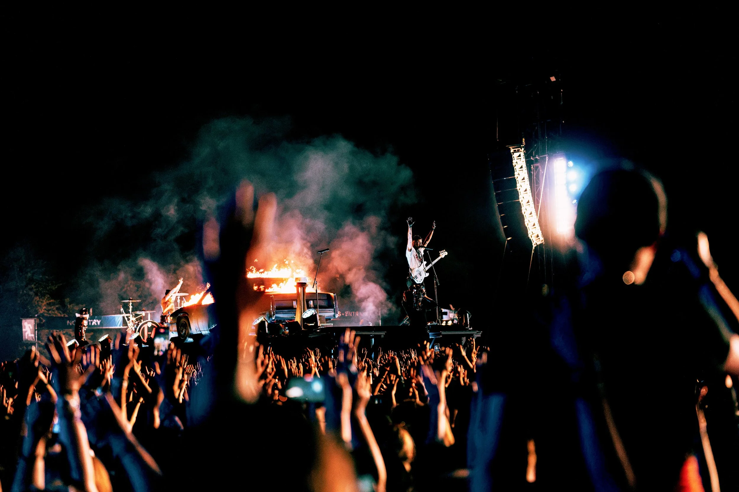 Twenty One Pilots performing at All Points East festival in Victoria Park, London in 2026, nighttime concert scene with a band performing on stage, colorful lights, smoke effects, and a crowd with raised hands enjoying the show.