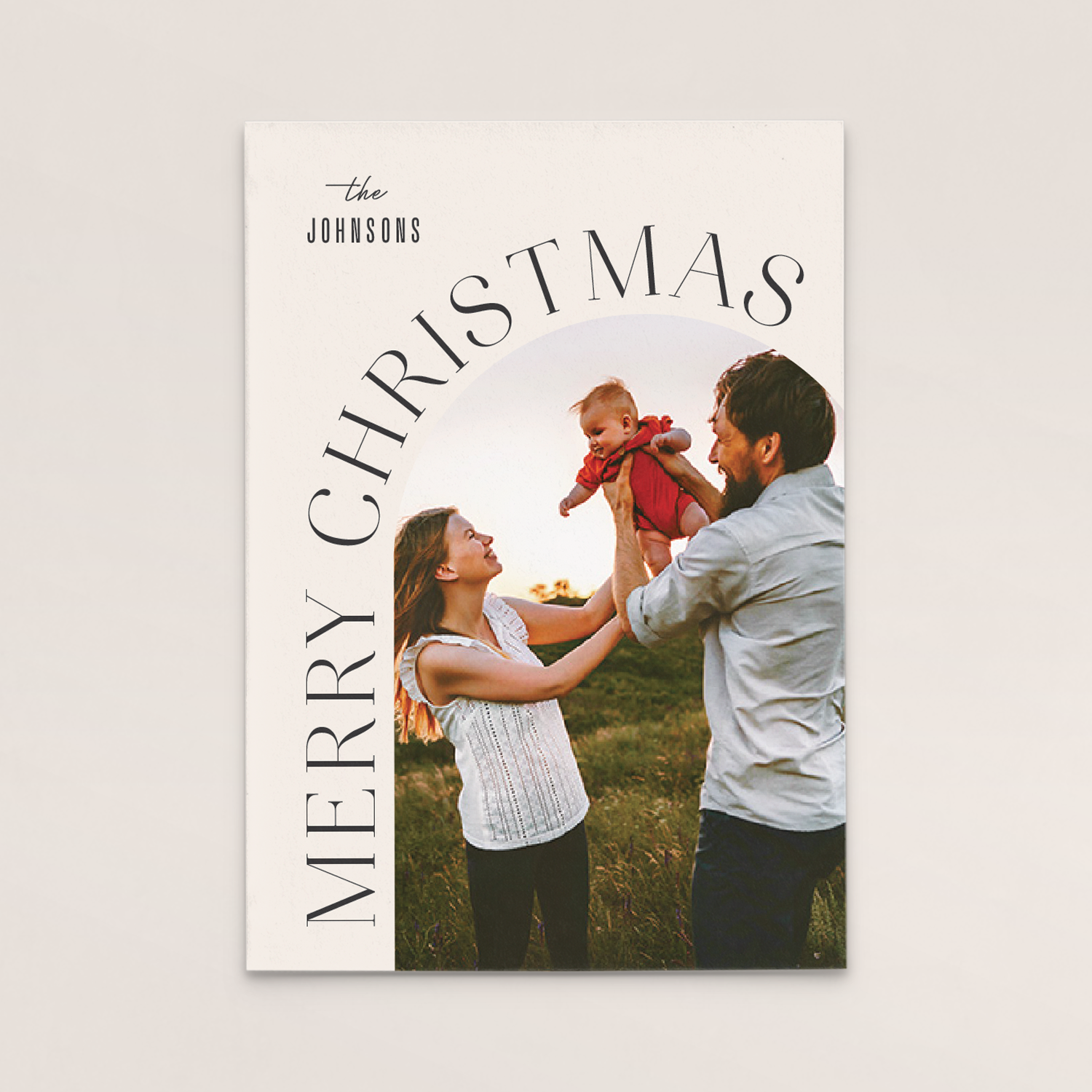 Family holding a baby outdoors during sunset, with text overlay saying 'Merry Christmas' and 'the Johnsons'.