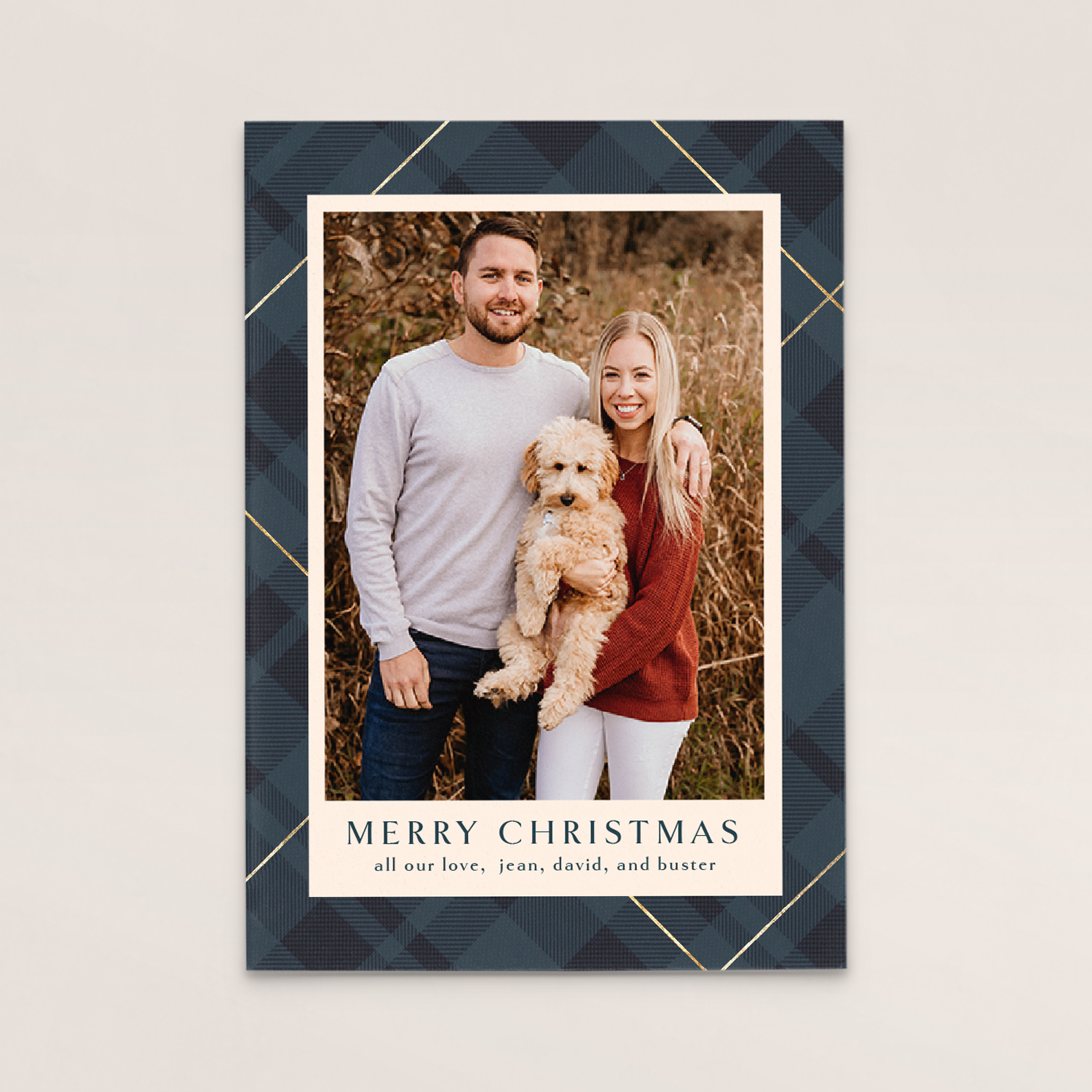 A Christmas card featuring a couple and their dog outdoors in a field of tall grass, smiling at the camera. The card says "Merry Christmas" and includes a message from their family, Jean, David, and Buster.