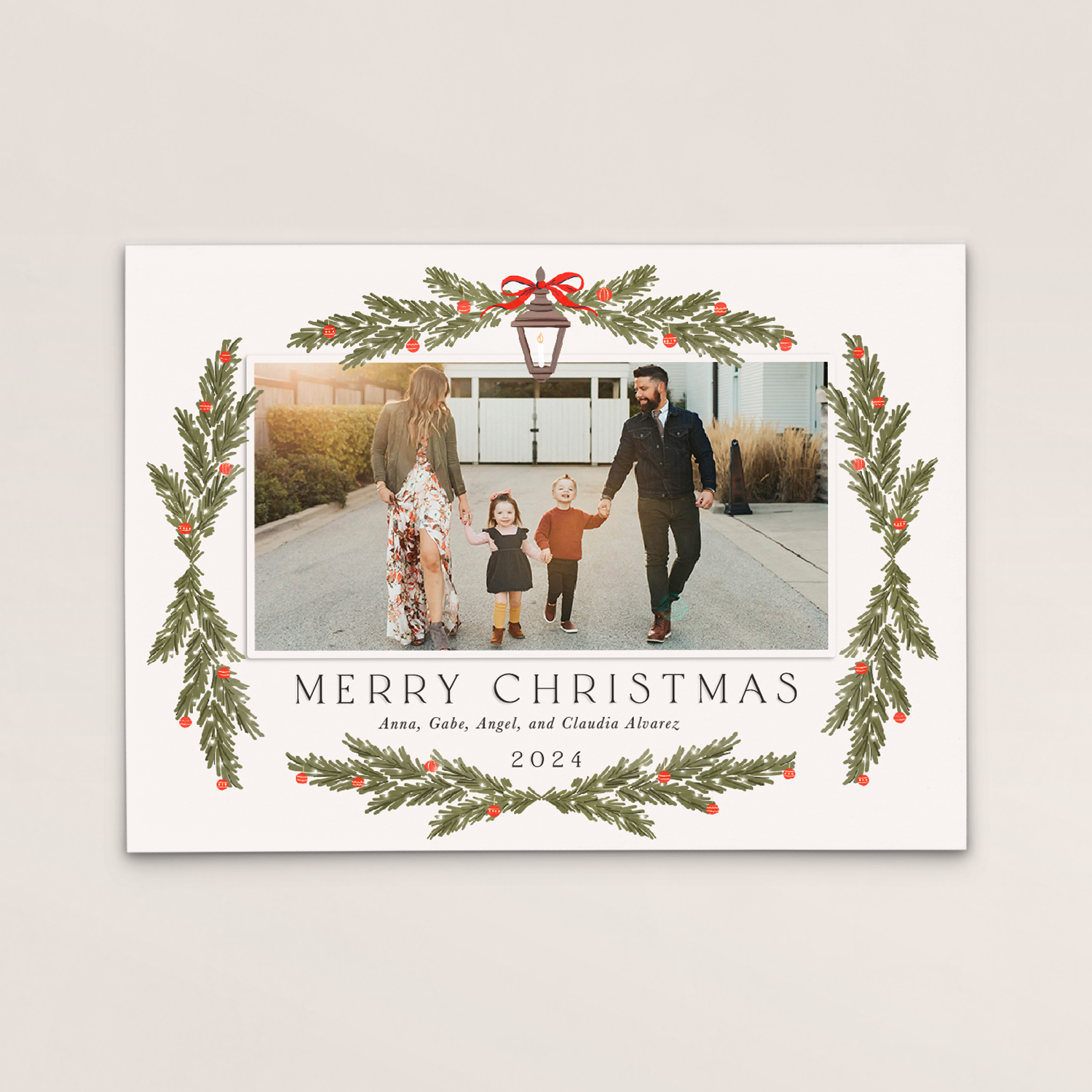 A personalized Christmas card featuring a family photo of a man, woman, and two children walking outdoors, surrounded by holiday-themed greenery and decorations, with text reading "Merry Christmas" and the names Anna, Gabe, Angel, and Claudia Alvarez