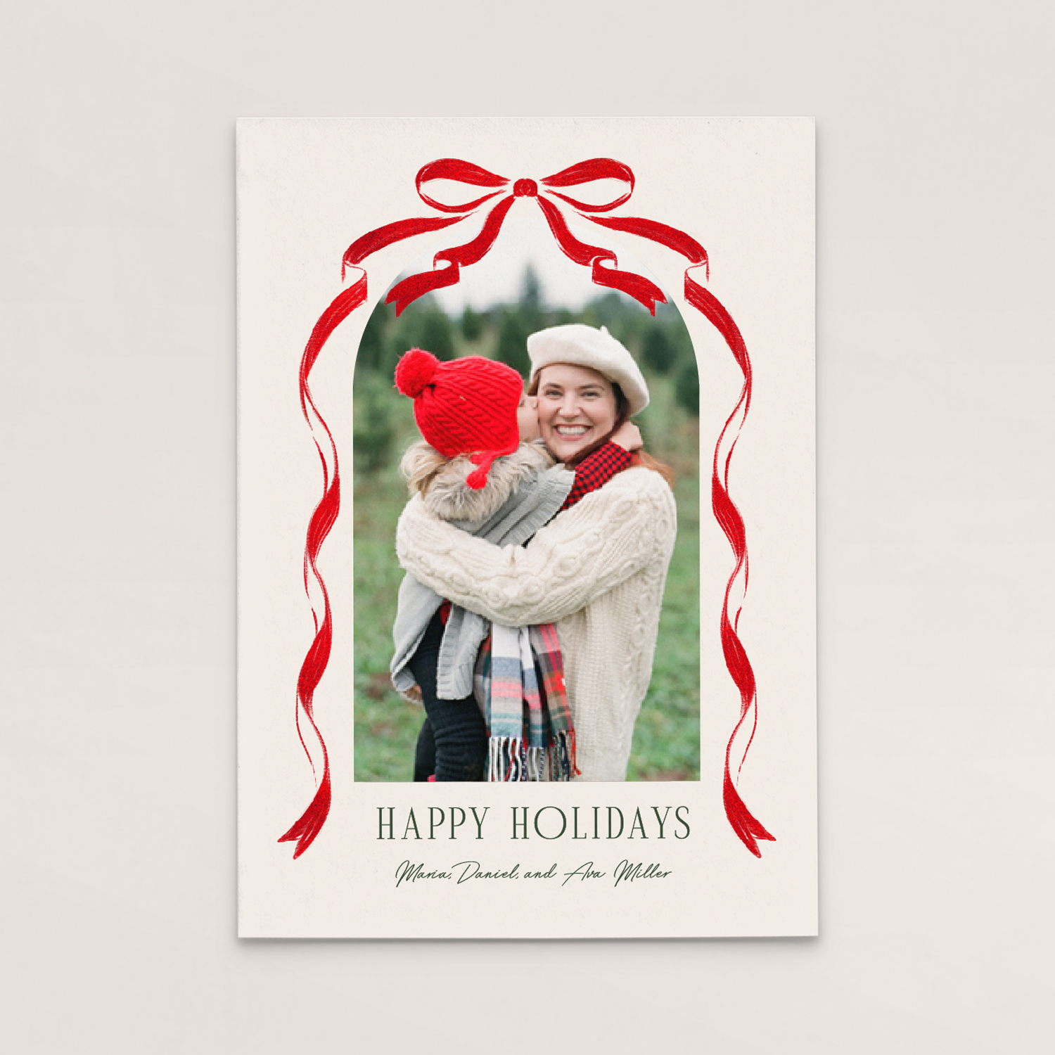 A holiday greeting card with a photo of a woman and a child hugging outdoors, surrounded by a decorative red ribbon and bow, with the message 'Happy Holidays' and personalized names 'Maria Daniel and Ava Miller'.