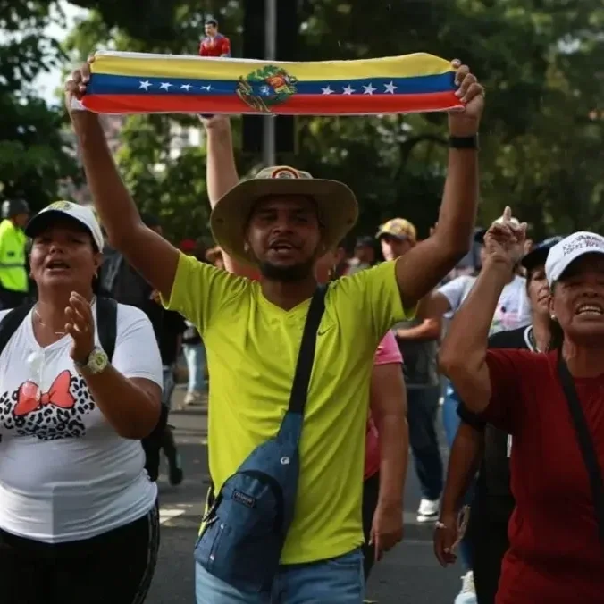 People marching, one of them holding the Venezuelan flag