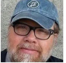 A man with a white and red beard wearing glasses and a baseball cap