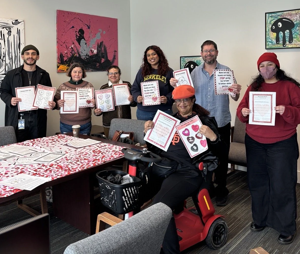 A multiracial group of people holding up valentine cards in an office.