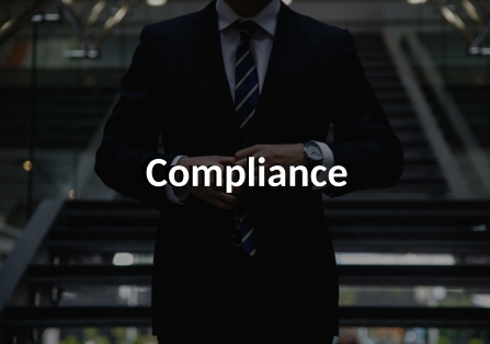 A man in a suit standing in front of a stair way. The image is darkened, and features the word Compliance  written over it.