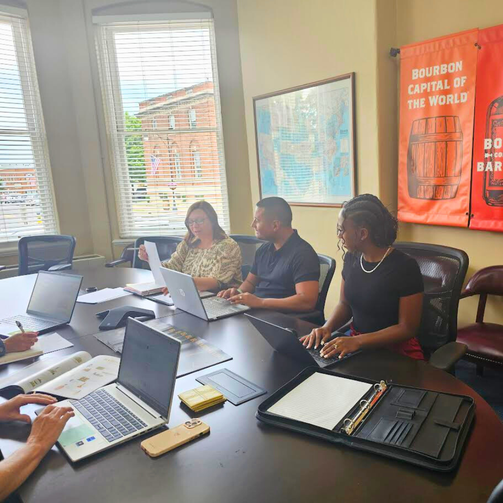 Individuals sitting around a conference table. They are at an event hosted by Shelly.
