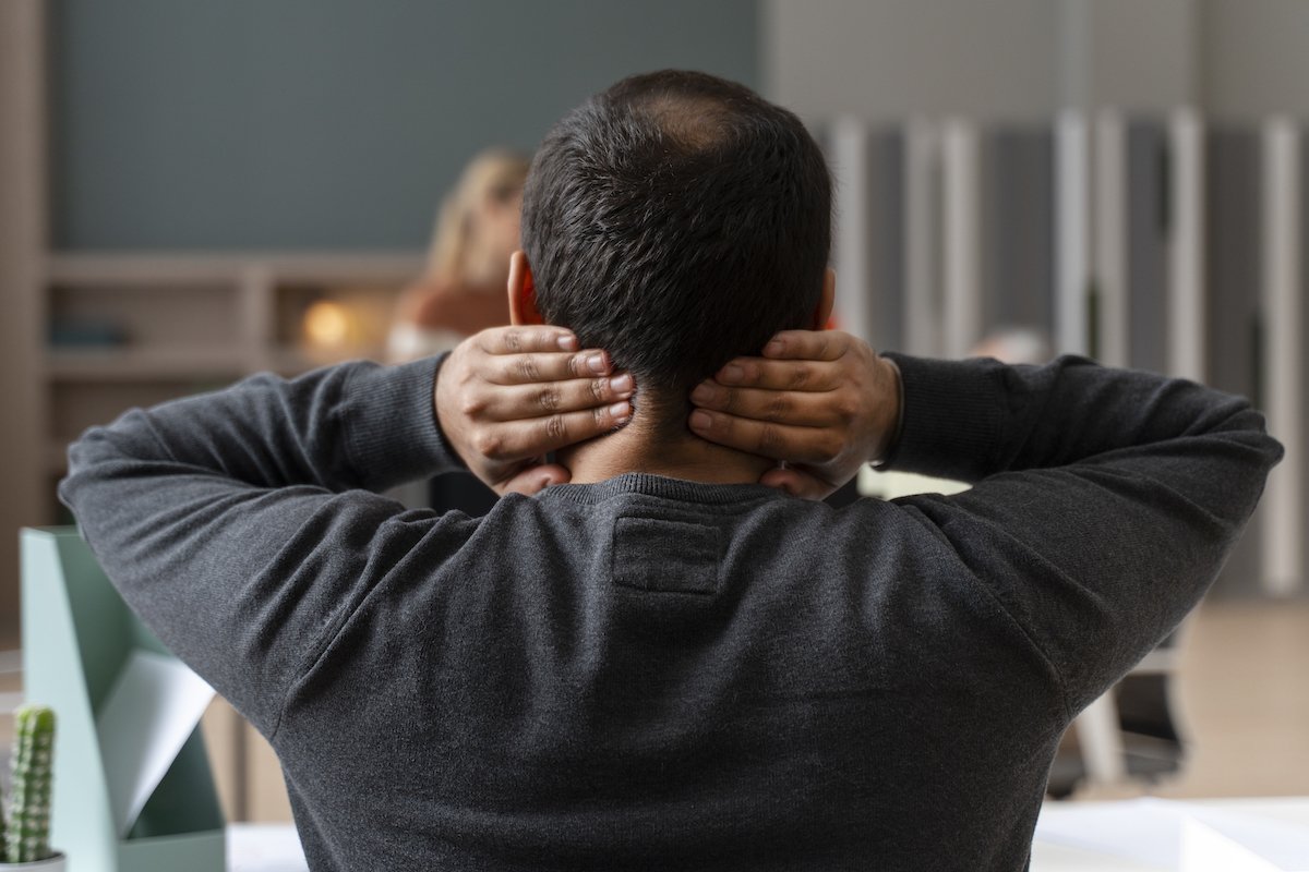 An image of a man facing away with his hands on his neck, signifying the pain that can be caused by an auto injury and the relief that Repose therapies can provide.