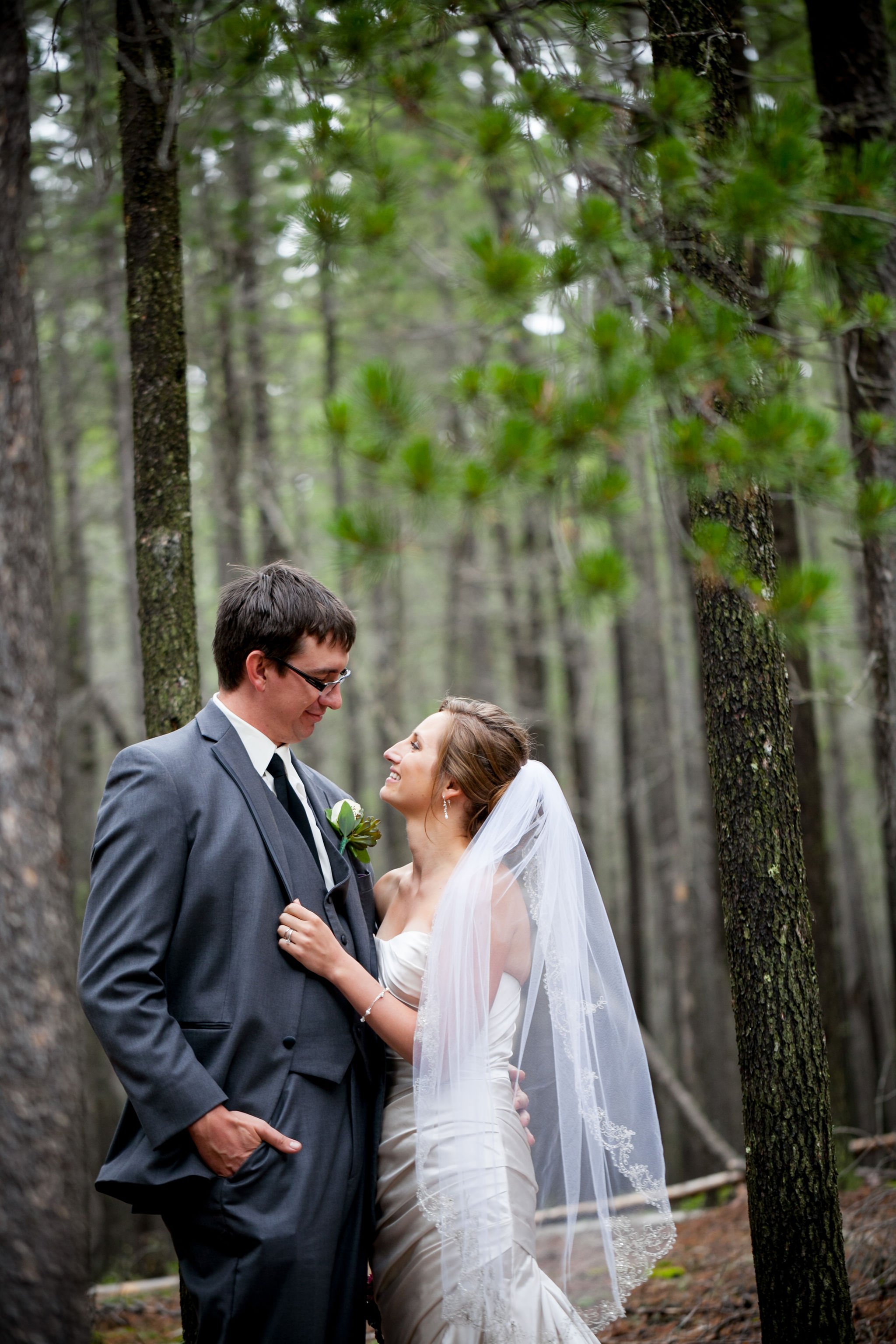 Bride and groom embracing in a forest setting.