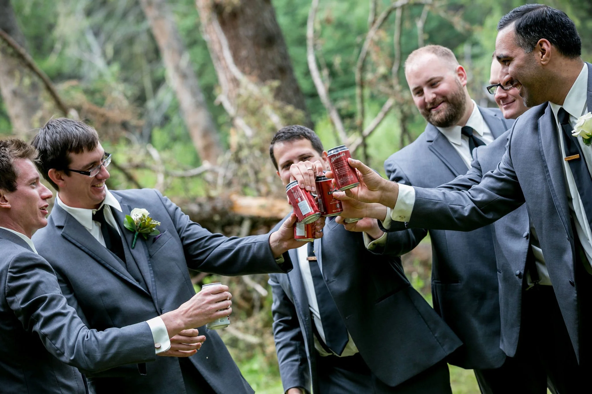 Group of groomsmen toasting with drinks outdoors