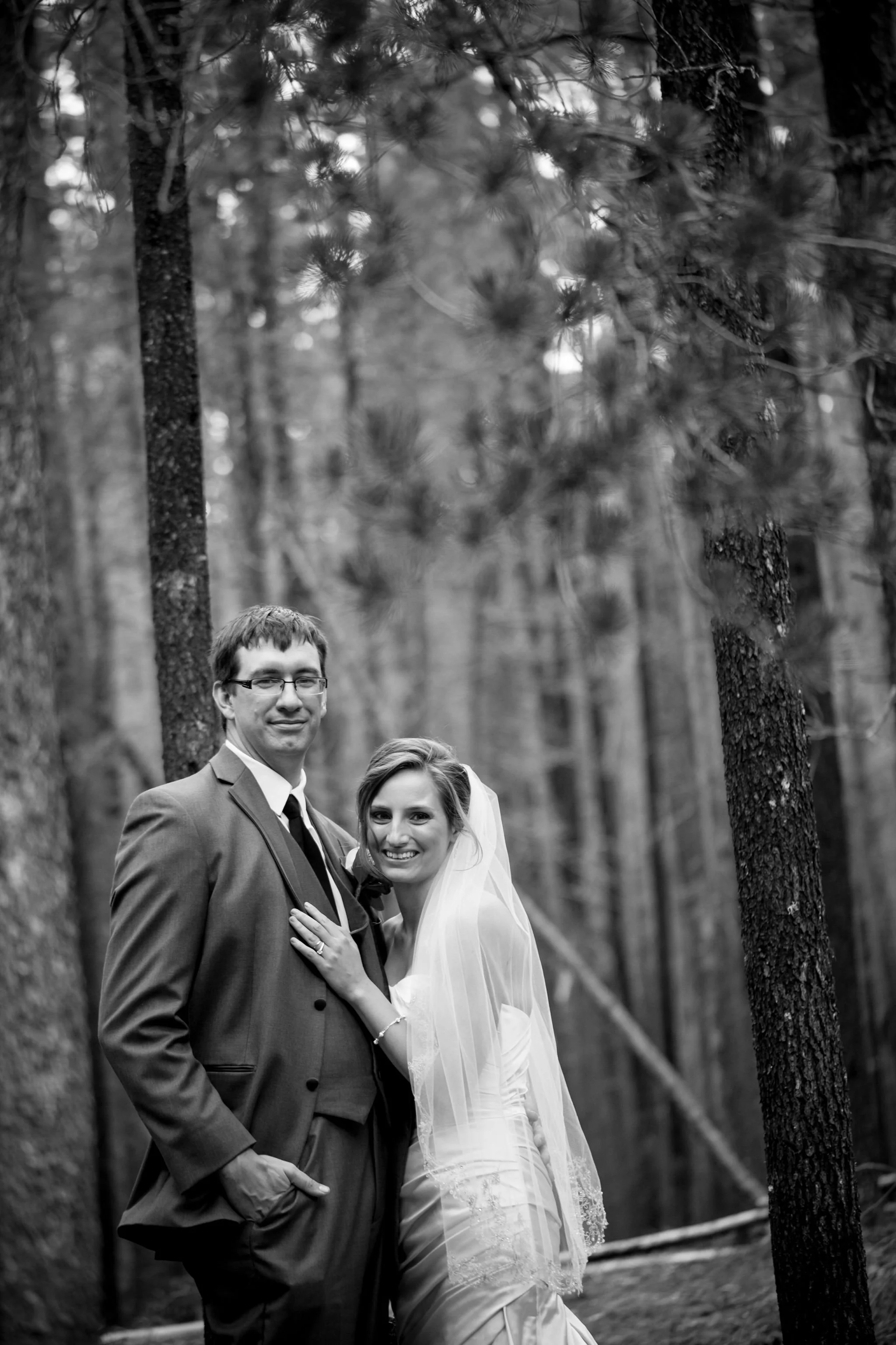 Bride and groom pose in forest setting, black and white photo in Cypress Hills, SK.
