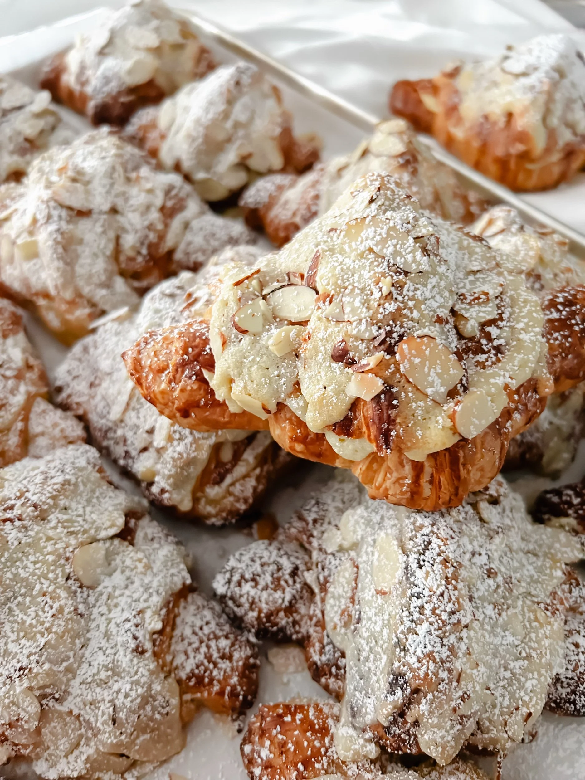 Close-up of assorted pieces of flaky pastry with powdered sugar and sliced almonds.
