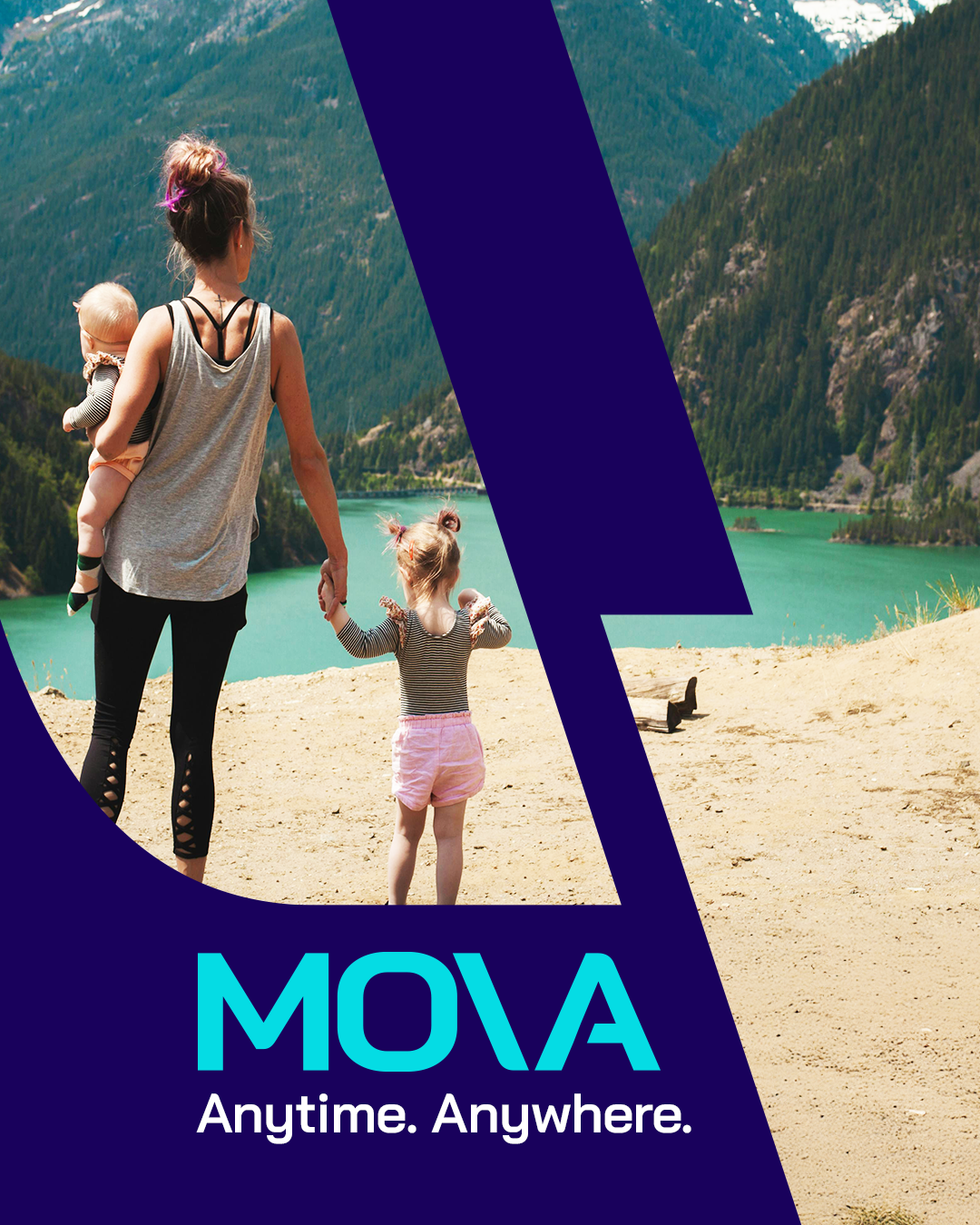 A woman holding a baby and a young girl walking on a sandy beach by a turquoise lake surrounded by mountains.