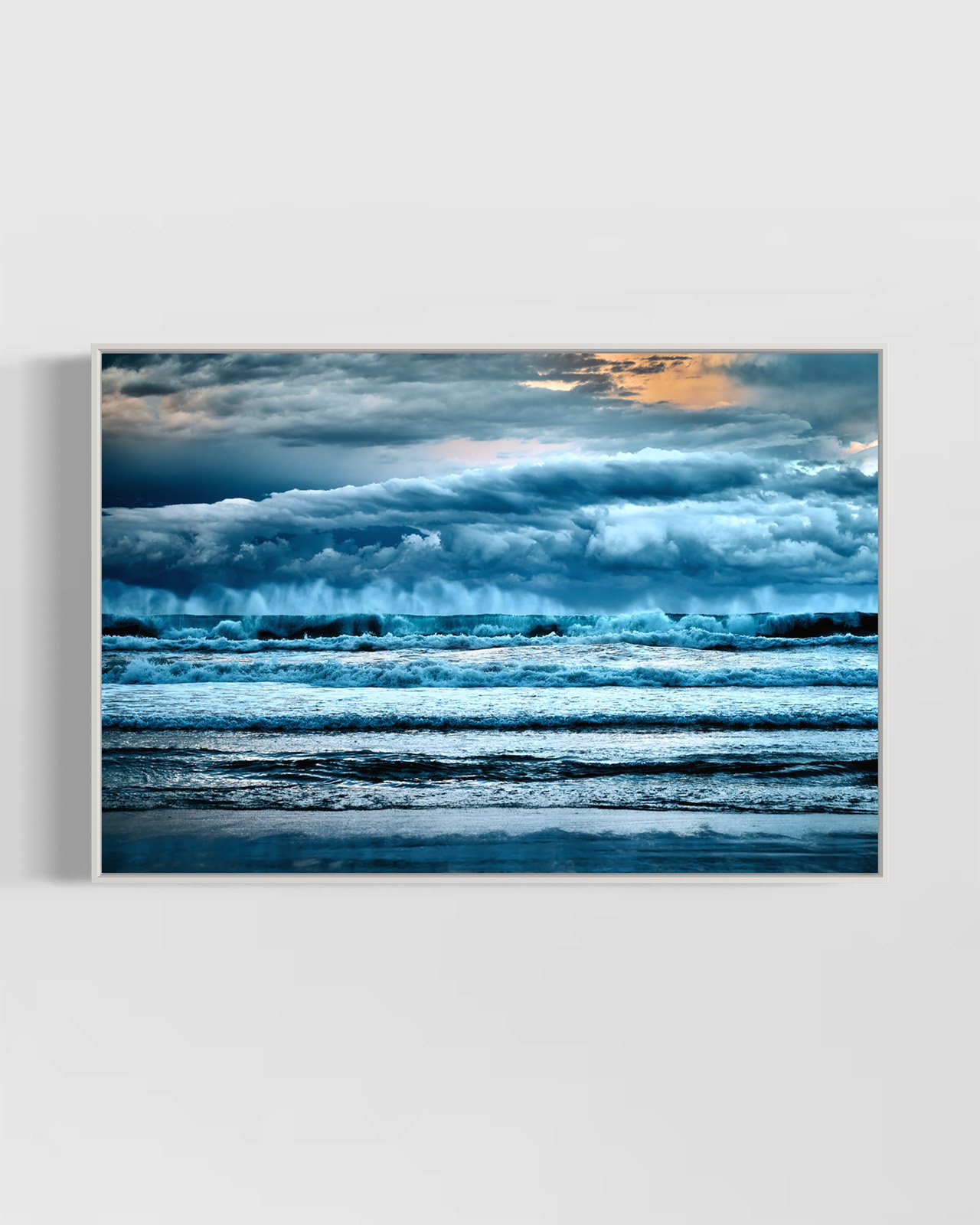 "Transcendence" photographic wall art in a white handcrafted frame. The artwork depicts storm clouds gathering above crashing ocean waves at Pambula Beach.
