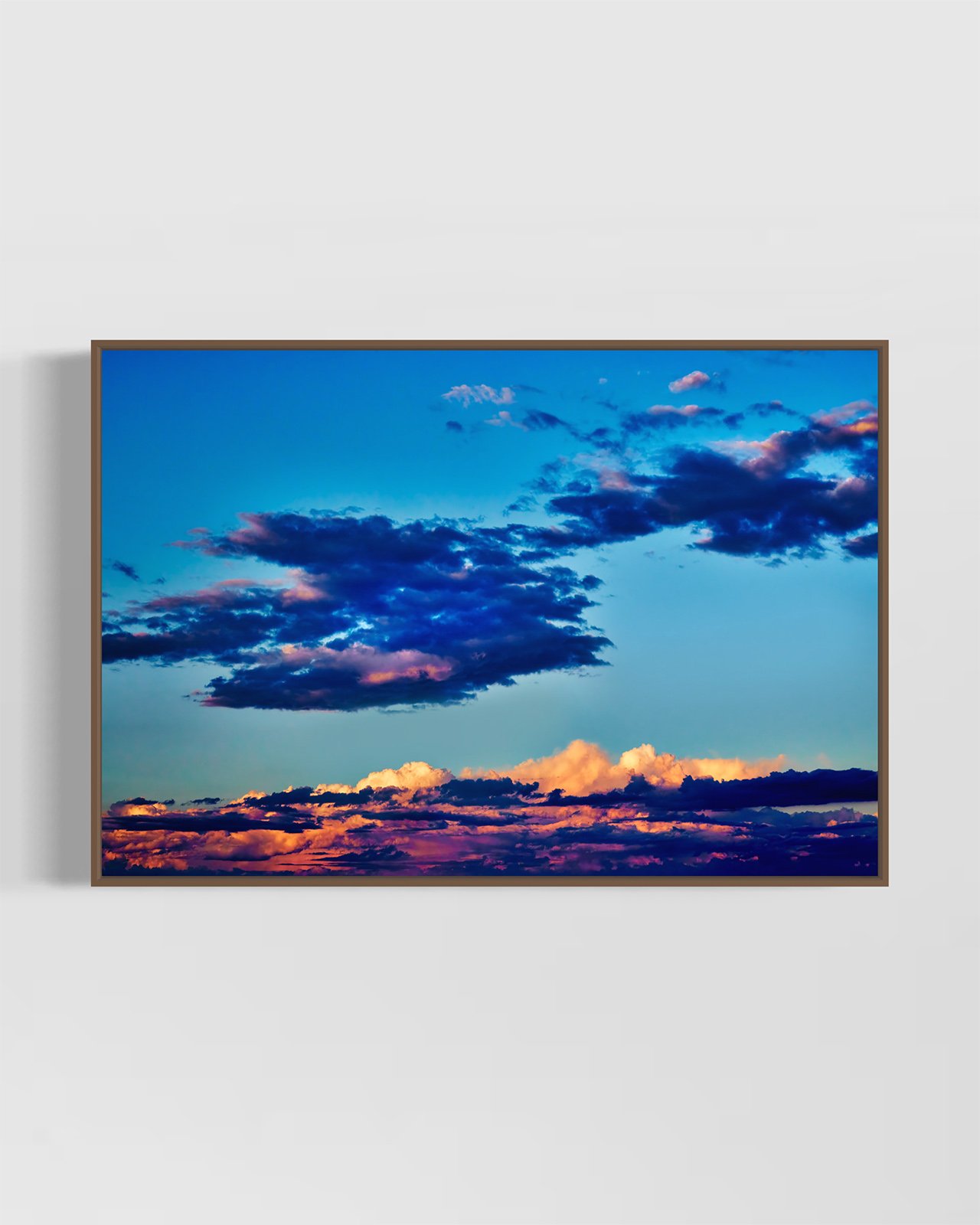 "Sky Sublime" photographic wall art, in a handcrafted walnut frame. The artwork depicts richly colourful sunset clouds in a blue sky at Pambula Beach.