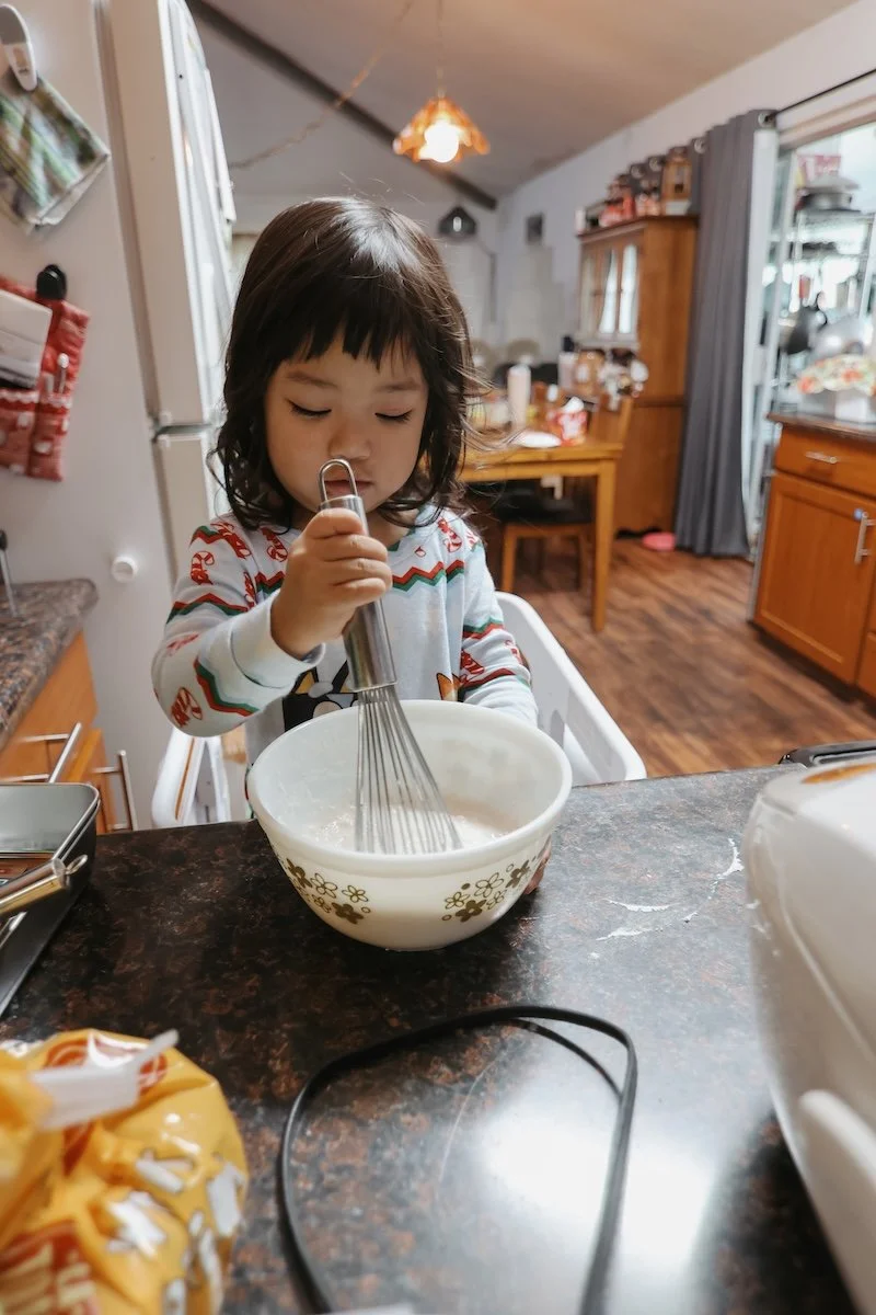 Toddler mixing pancake mix.