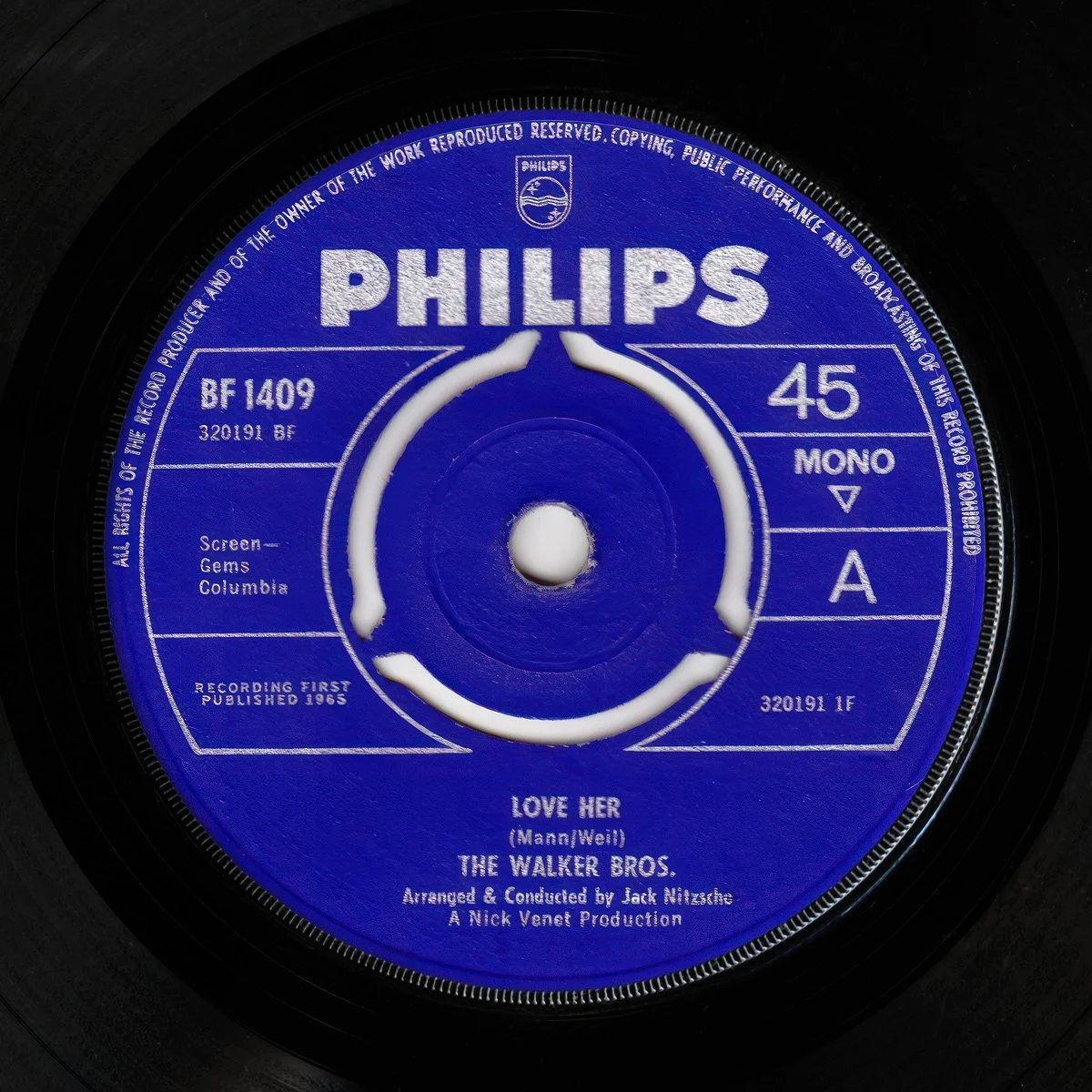 Close-up of a vintage Phillips vinyl record label, blue with white text, titled 'Love Her' by The Walker Bros, arranged and conducted by Jack Nitzsche.