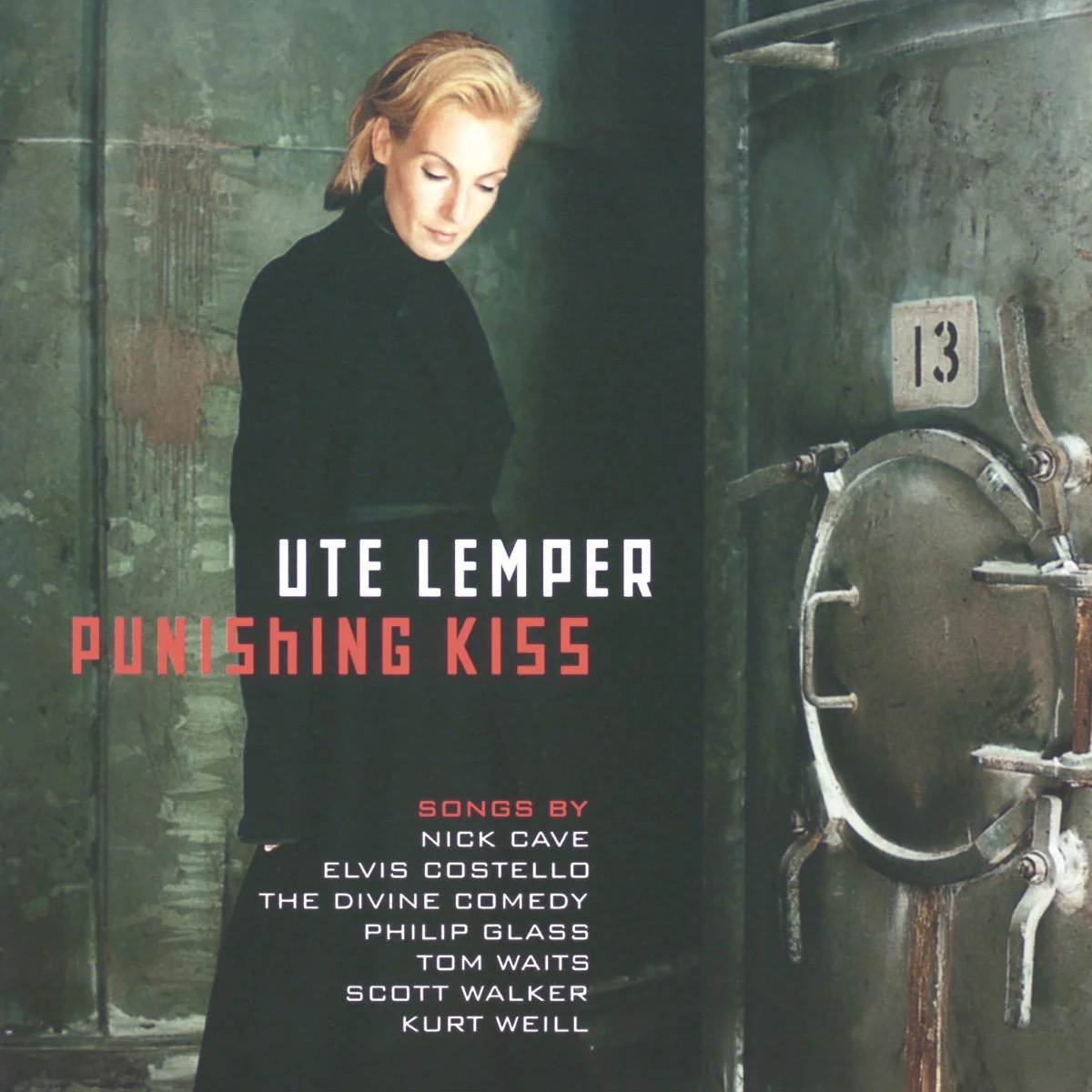 Album cover for 'Punishing Kiss' by Ute Lemper, featuring Ute with short blonde hair in a black outfit standing in front of a gritty, industrial-style wall and a vault door.
