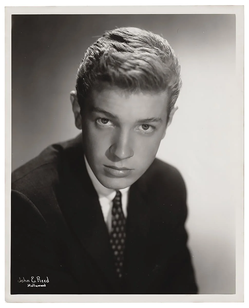 Posed black and white promotional portrait of a young Scott Walker, taken around 1958,  in formal attire, with slicked-back hair, looking directly at the camera.