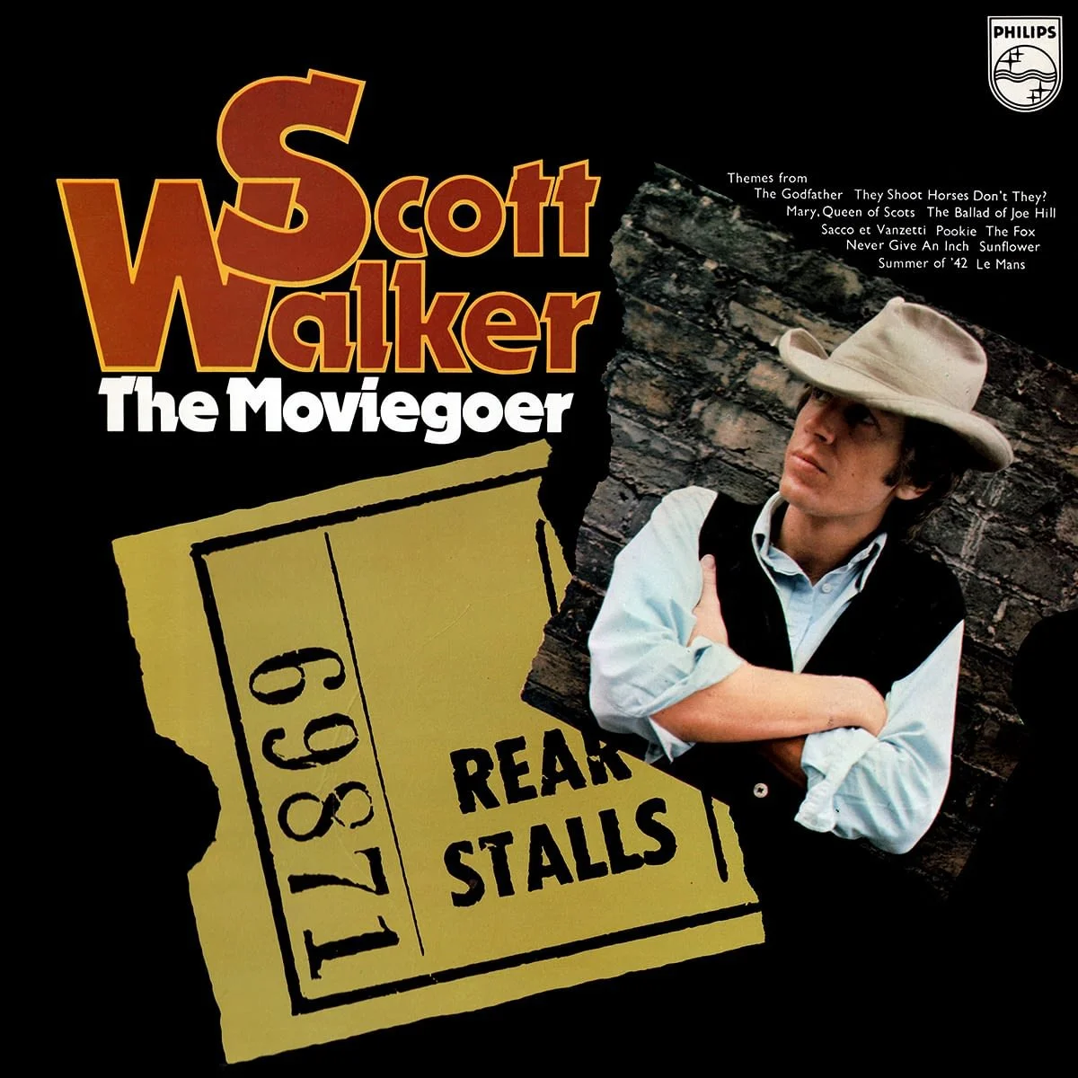 Album cover of 'Scott Walker: The Moviegester' featuring Scott wearing a cowboy hat with crossed arms, standing against a brick wall with a torn ticket featuring the number 1198 and the words 'Rear Stalls'.