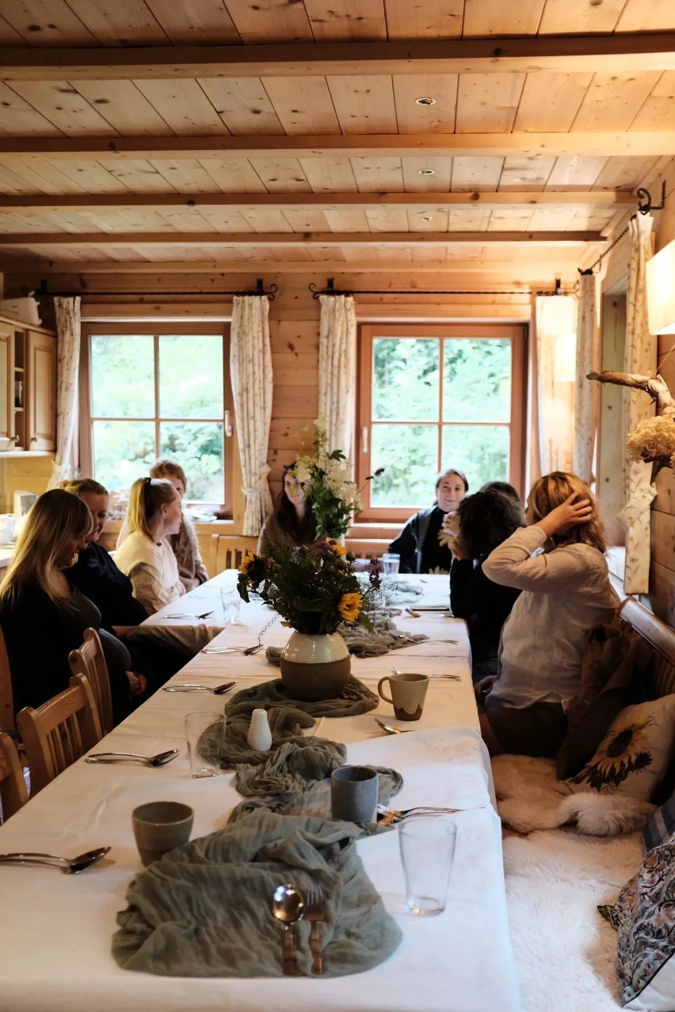 Frauen sitzen rund um einen schön gedeckten Tisch in einer rustikalen Hütte