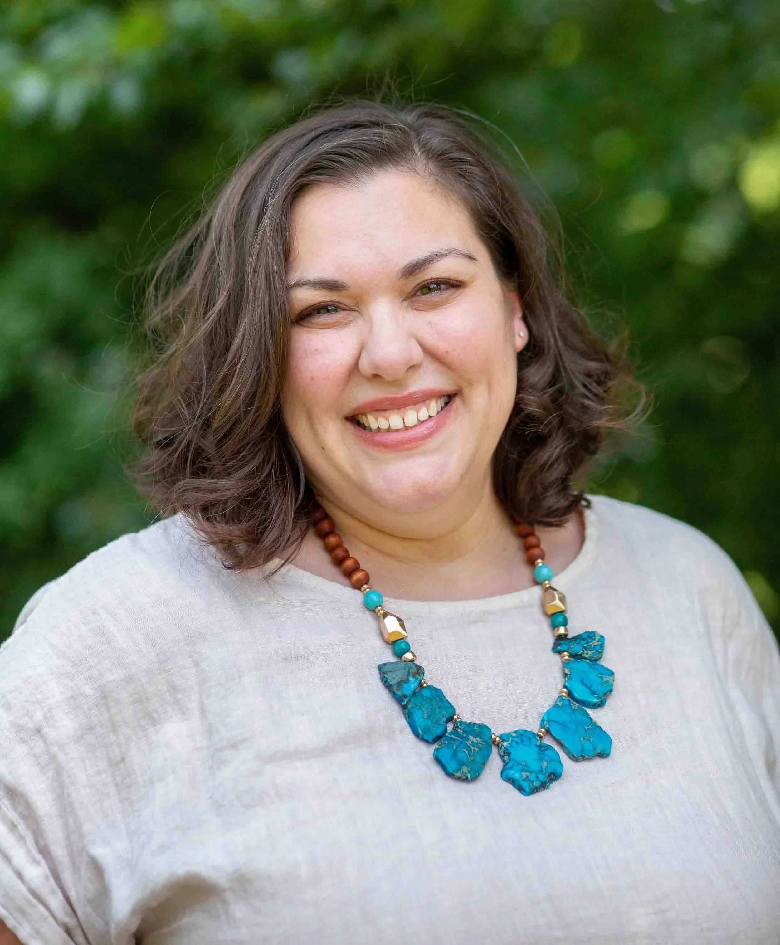 Woman with turquoise necklace and brown hair smiling