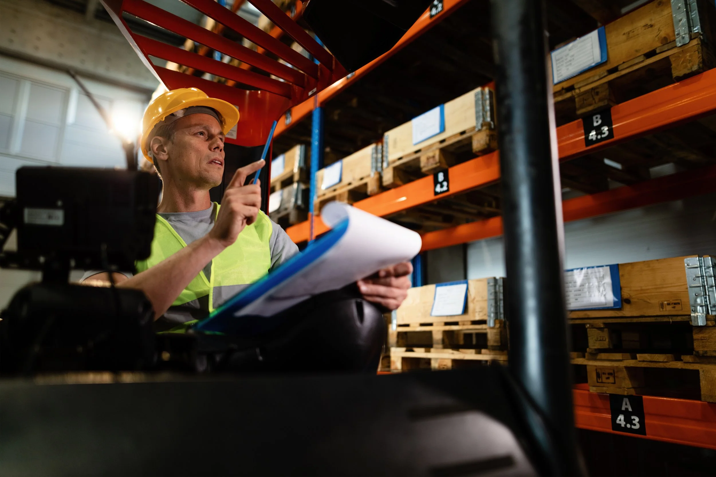 pensive-forklift-operator-examining-stock-packages-shelves-warehouse (1).jpg