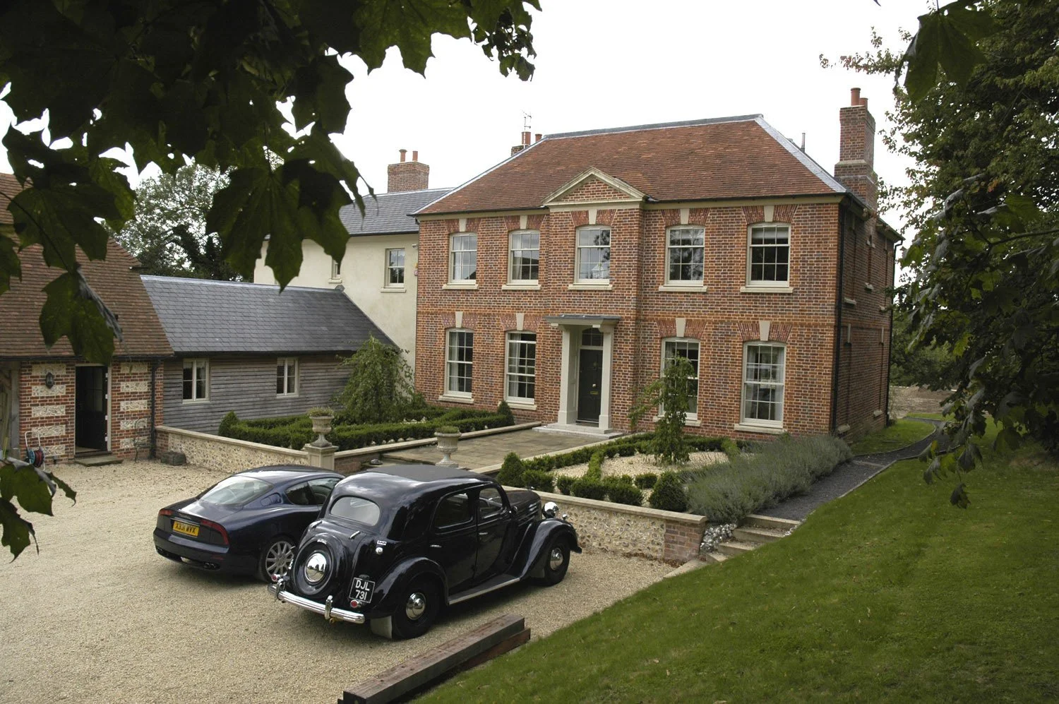 large two-story country house with classical architectural features and a landscaped garden.