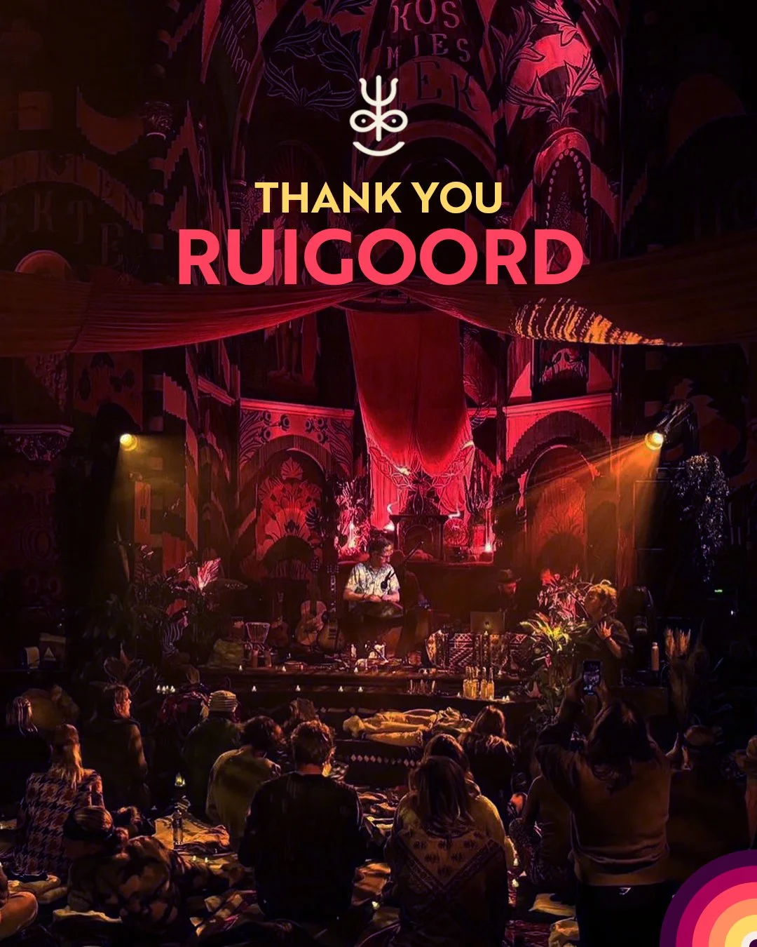 A stage with a musical performance under pink and purple lighting, with an audience sitting on the floor watching. The background features intricate, colorful wall art and draped fabrics. Text reads 'Thank You RUIGOORD' with a small abstract logo above.