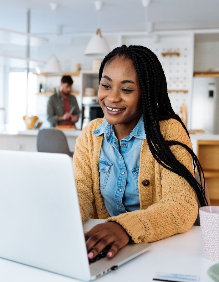 Middle aged women smiling looking at her laptop providing business coaching for therapists