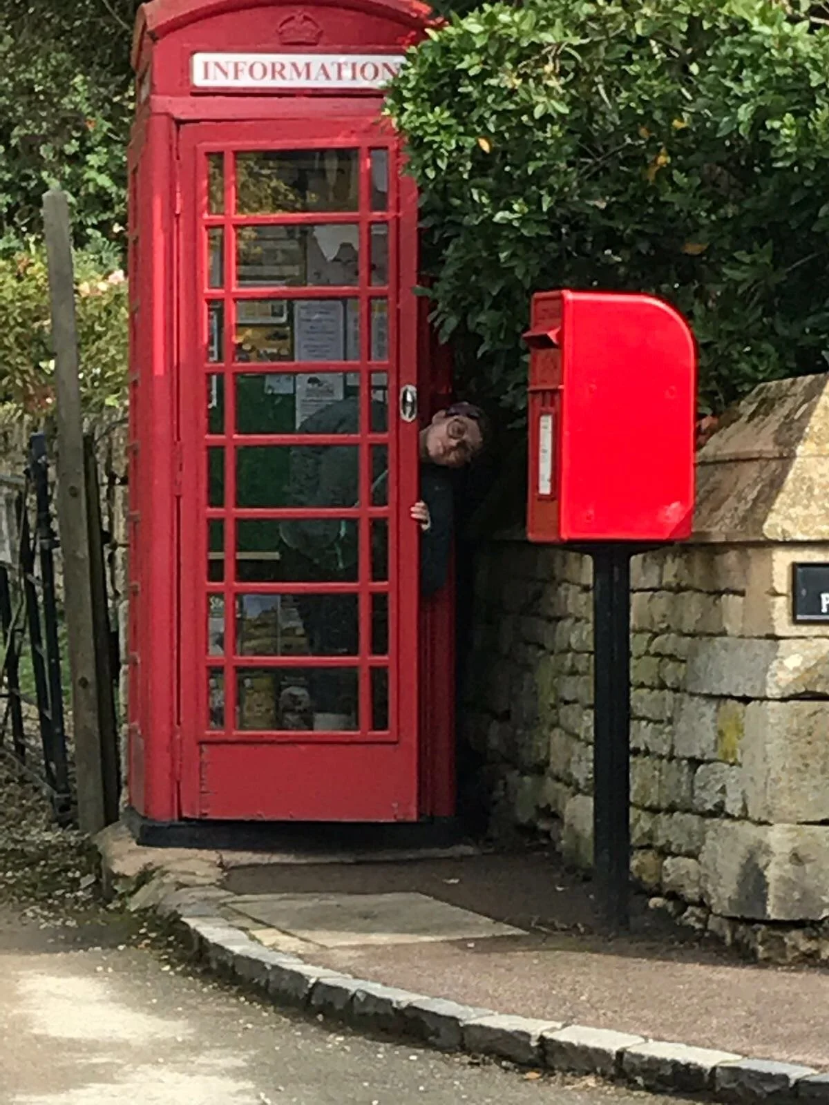 Woman peeking out of a telephone information box.