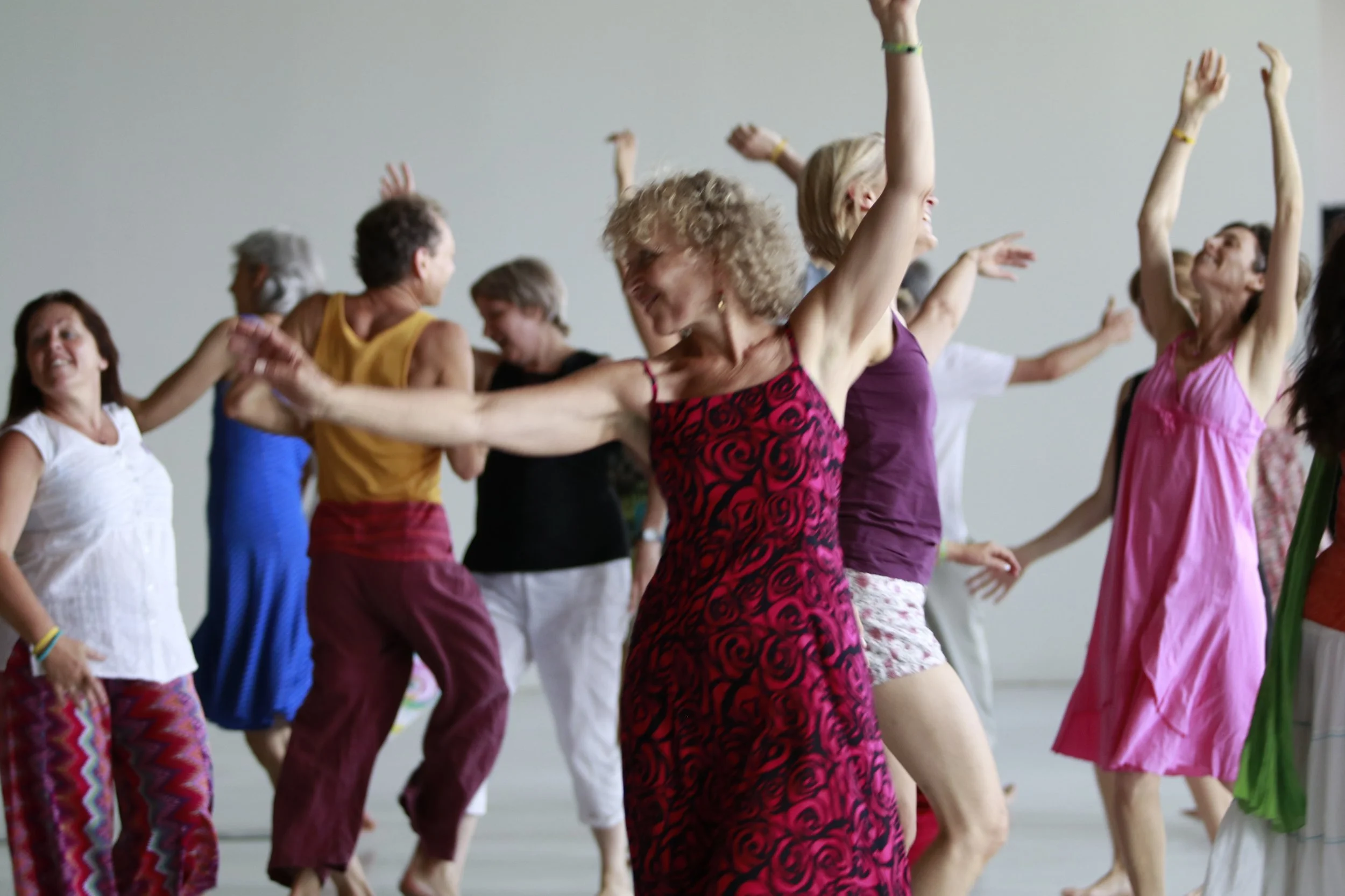 A group of adults dancing and enjoying themselves in a spacious, well-lit indoor setting.