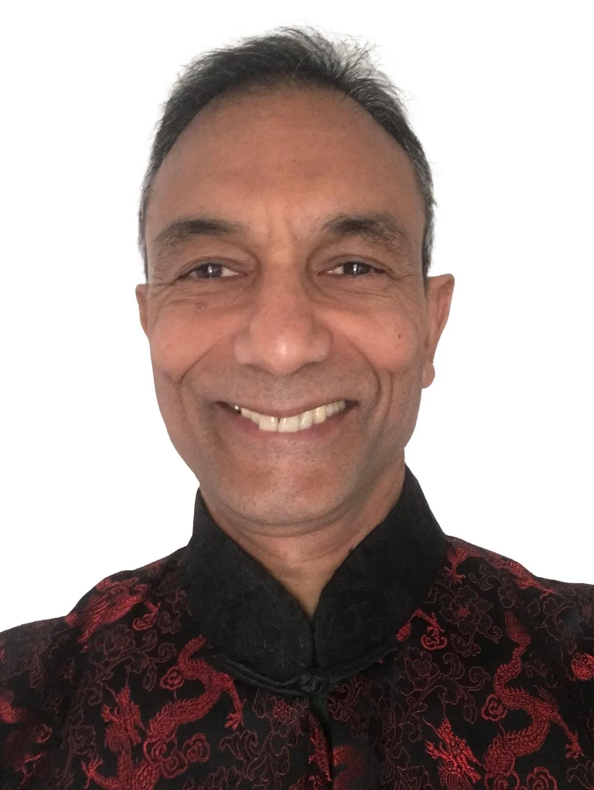 Close-up of a smiling man wearing a black patterned traditional Chinese jacket, with a white background. Altair De Almeida. Biodanza in Malvern