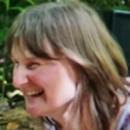 A woman with light brown hair smiling and looking to her left, outdoors. Pavani Lovegood, Biodanza Dorset