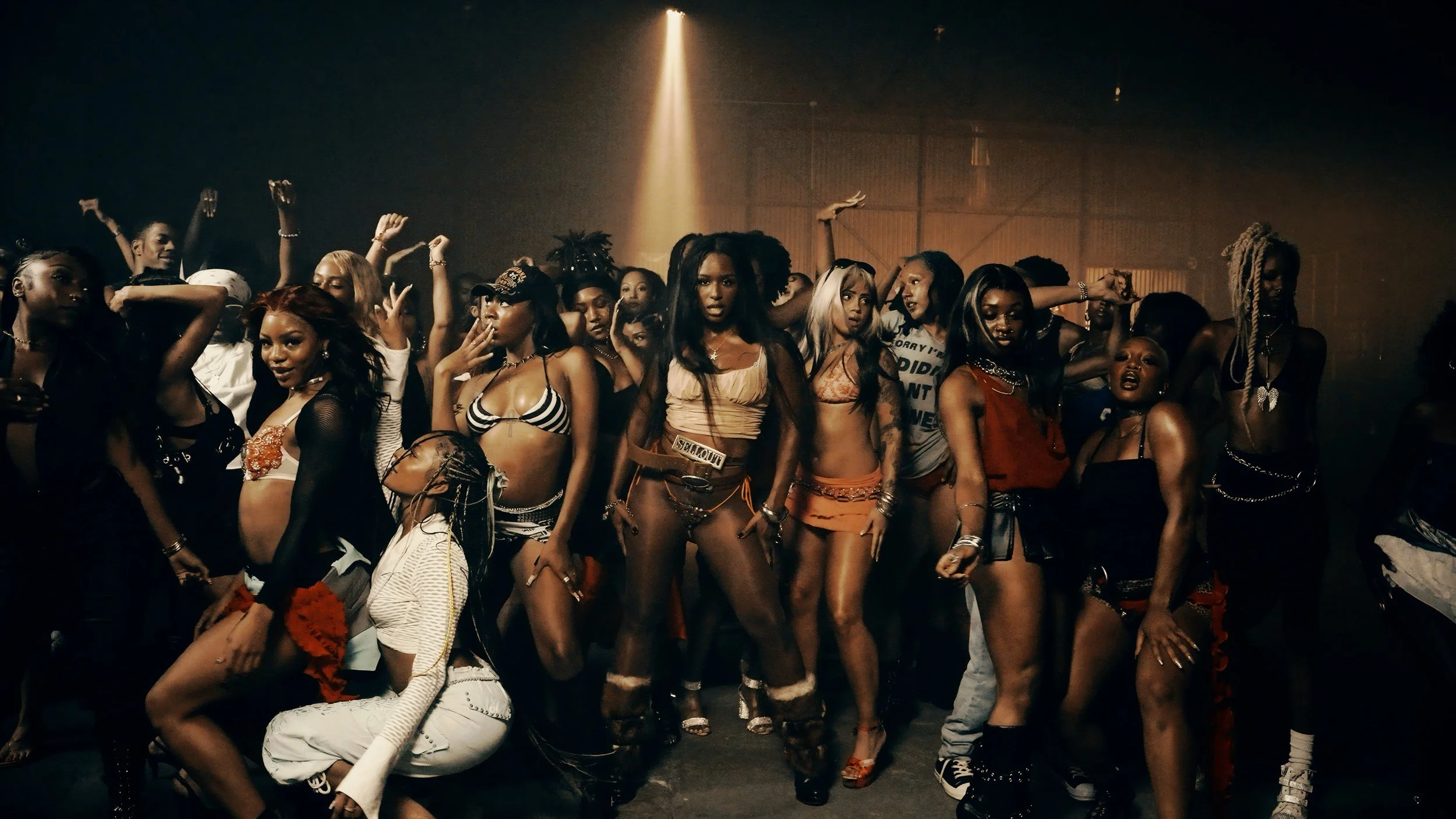 Group of women in revealing clothing dancing and posing in a dimly lit club or event space.