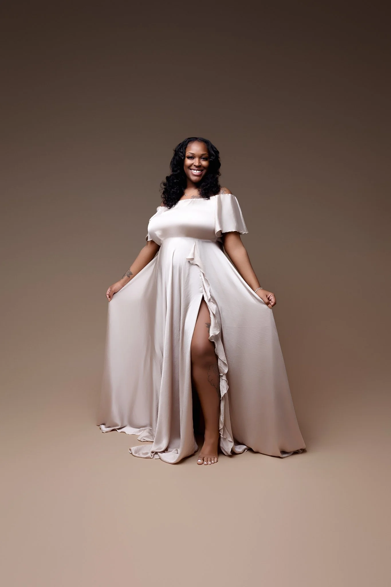 Pregnant woman is standing holding her silver dress.