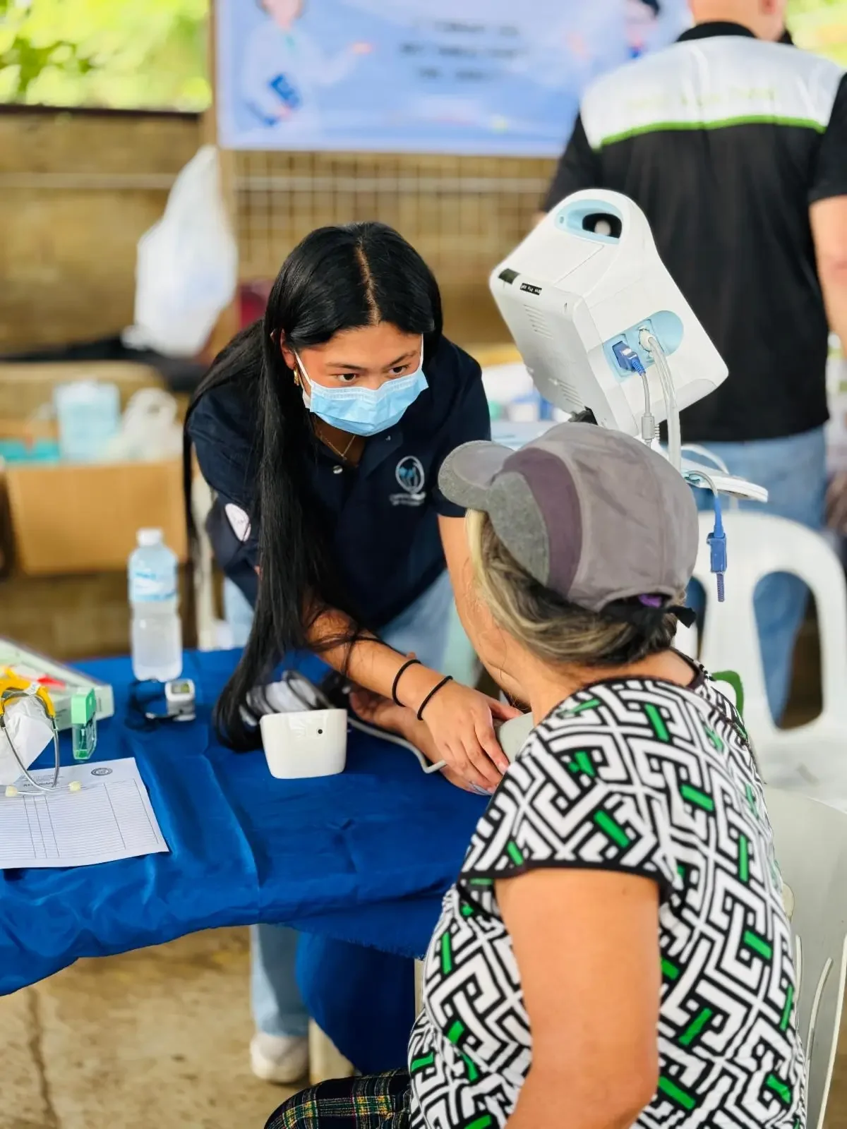Healthcare volunteer taking a patient's blood pressure during a free medical mission clinic in the Philippines