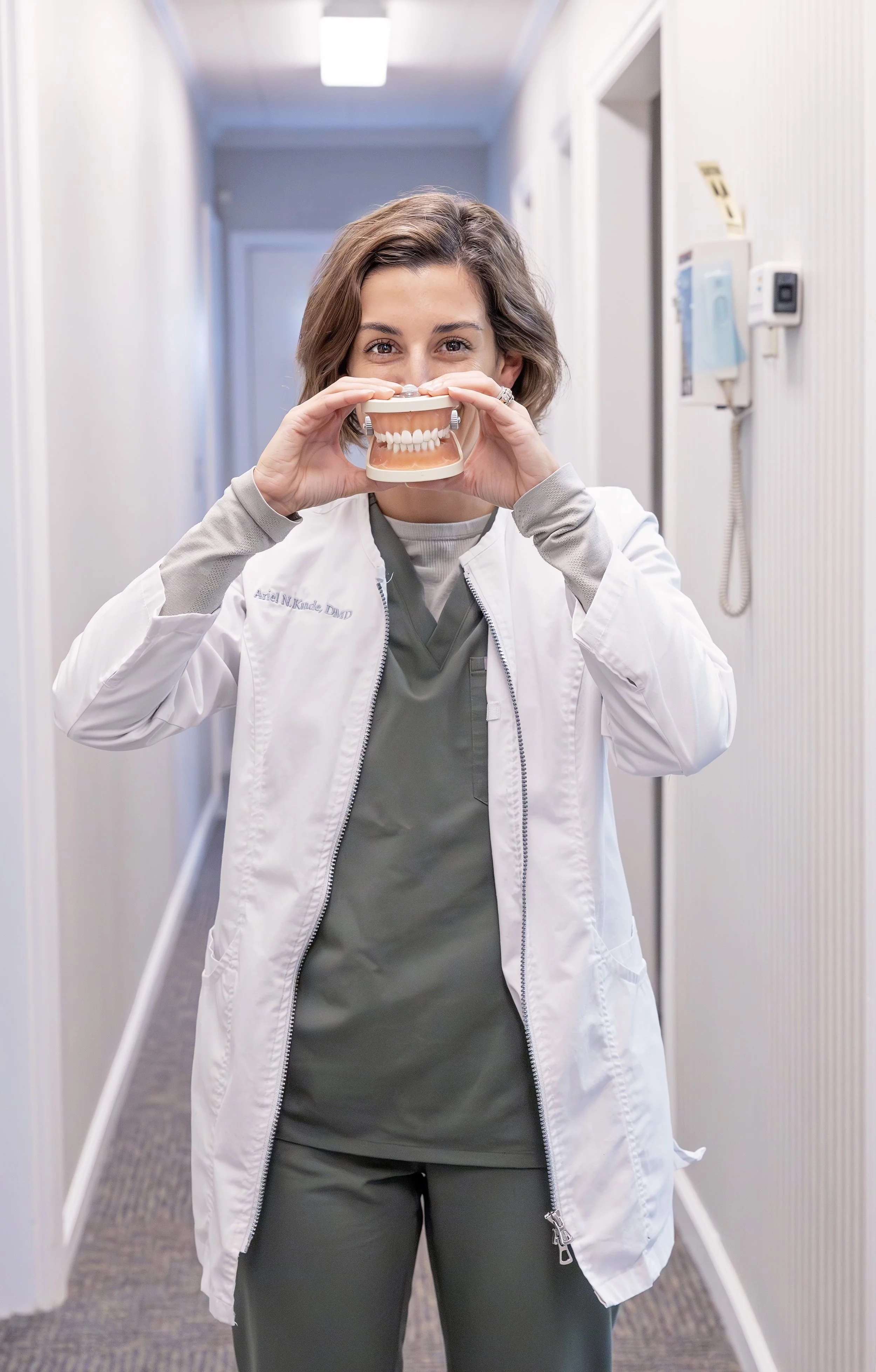 Dr. Ariel Kunde is holding a mouth model in front of her smile playfully