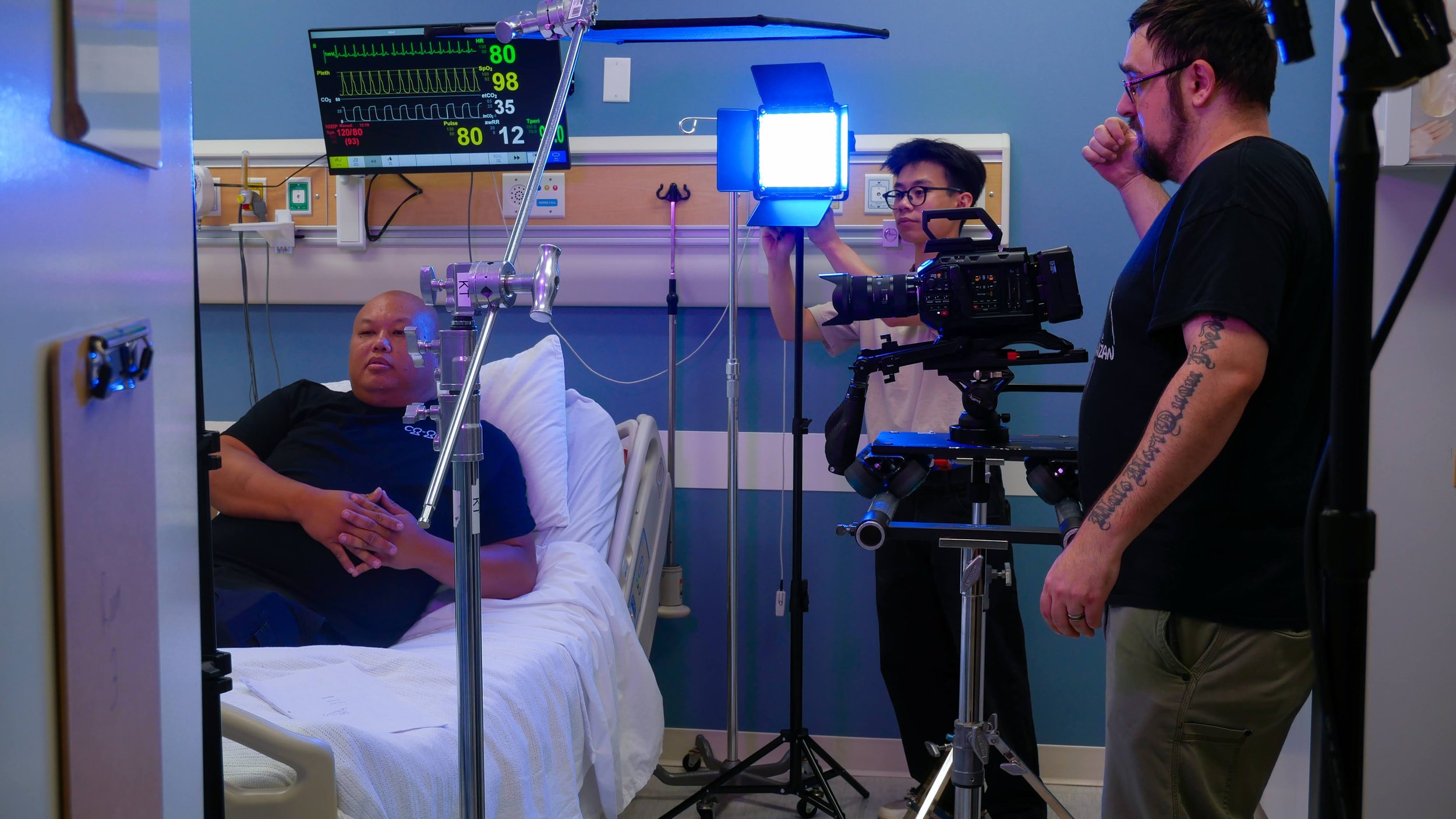 Camera crew positions a dolly and adjusts lighting in a sterile hospital hallway, preparing for a dramatic scene in In Reverie.