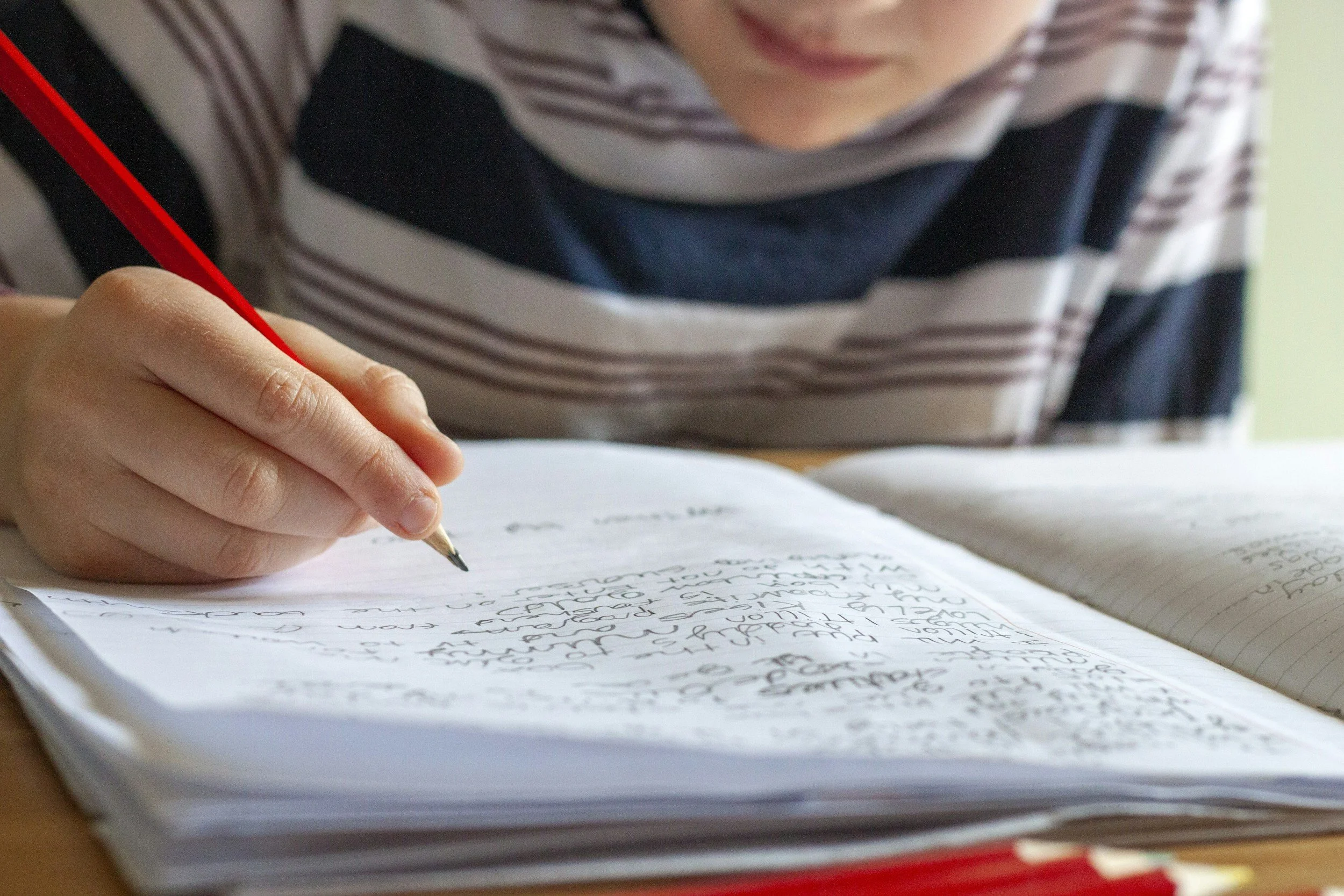 Close-up of a student writing in a notebook while drafting a college application essay