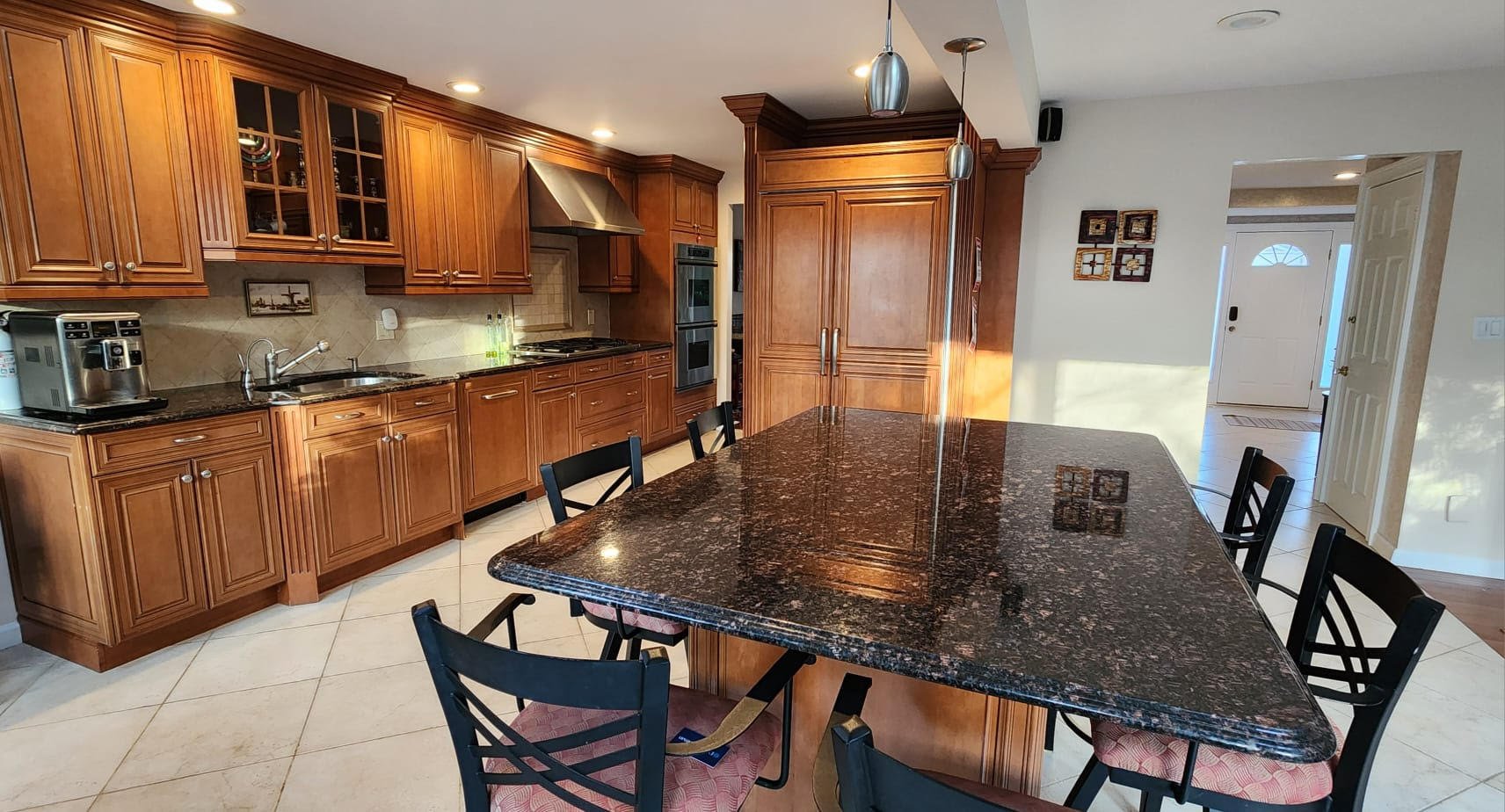 Modern kitchen with wooden cabinets, granite countertops, stainless steel appliances, and a large island with seating.