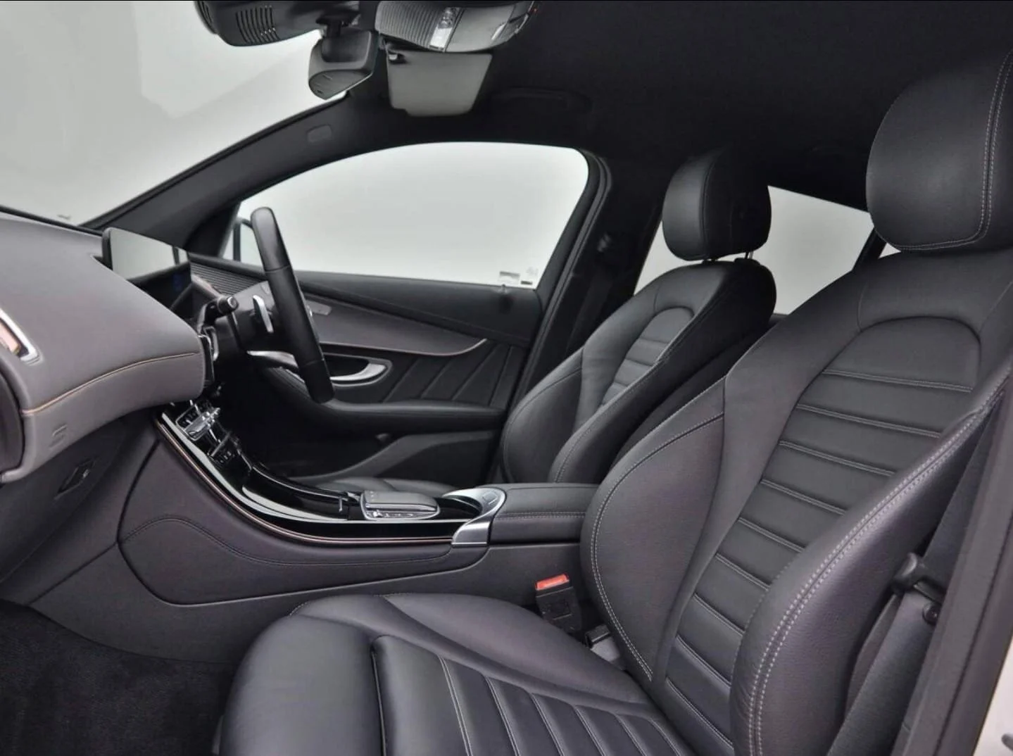 The interior of a luxury vehicle showing the front passenger and driver seats, dashboard, steering wheel, and center console with a modern design and black leather upholstery.