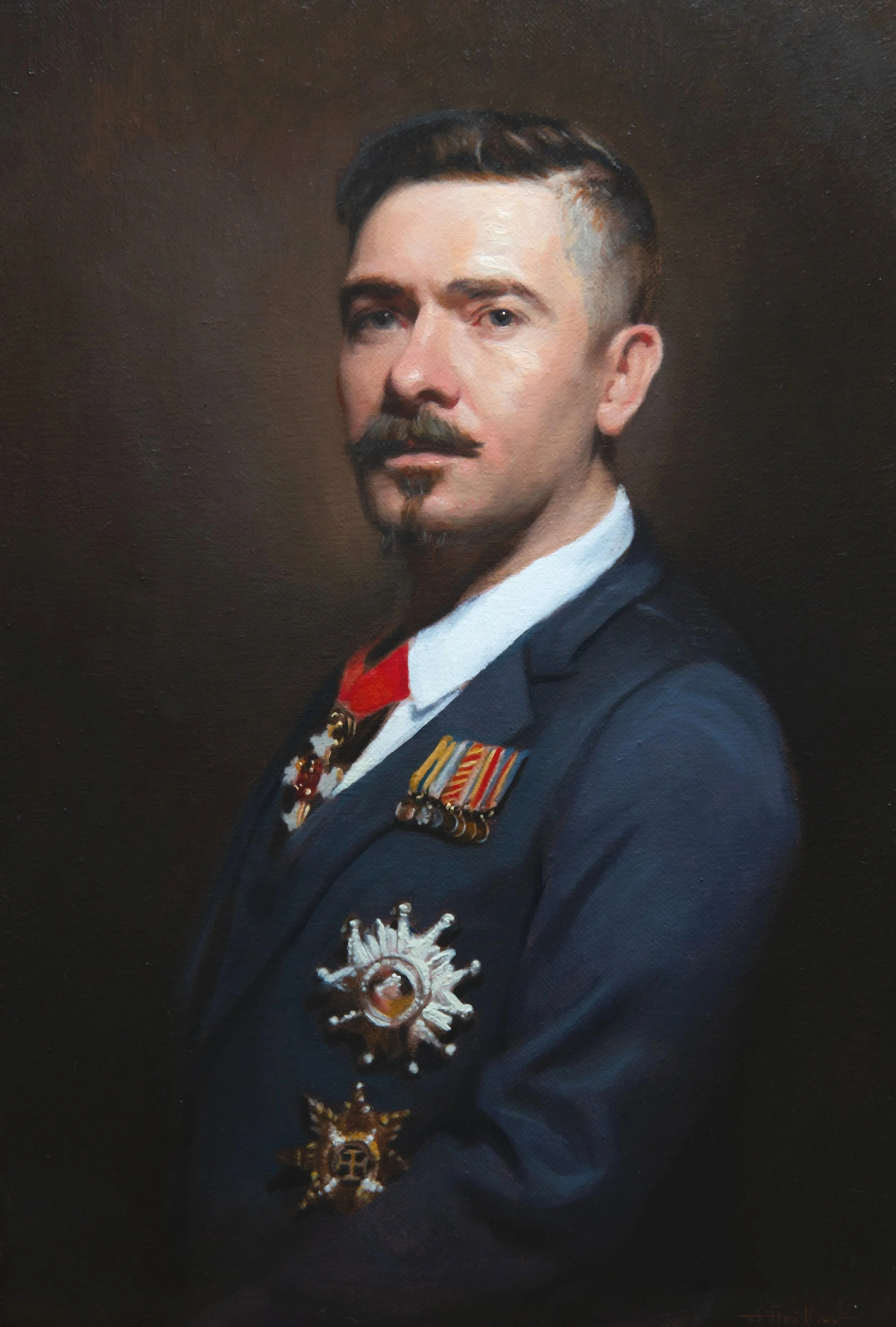 Portrait of a man wearing a formal suit with medals and decorations, with dark hair and a mustache, against a dark background.