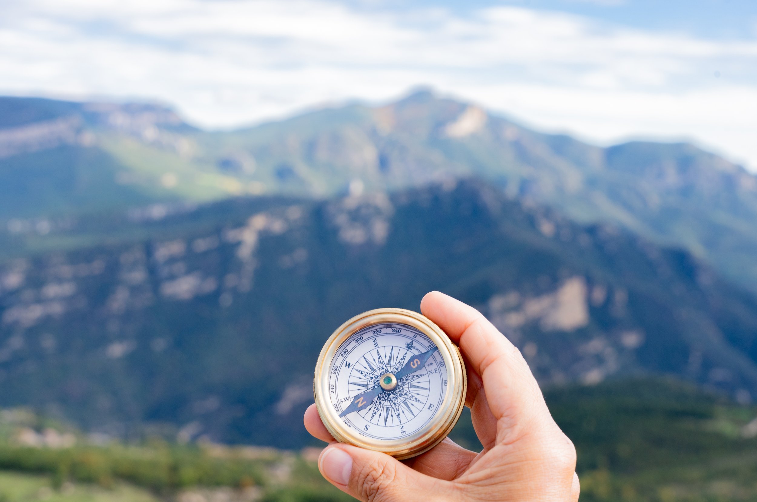 Hand holding compass with mountain view