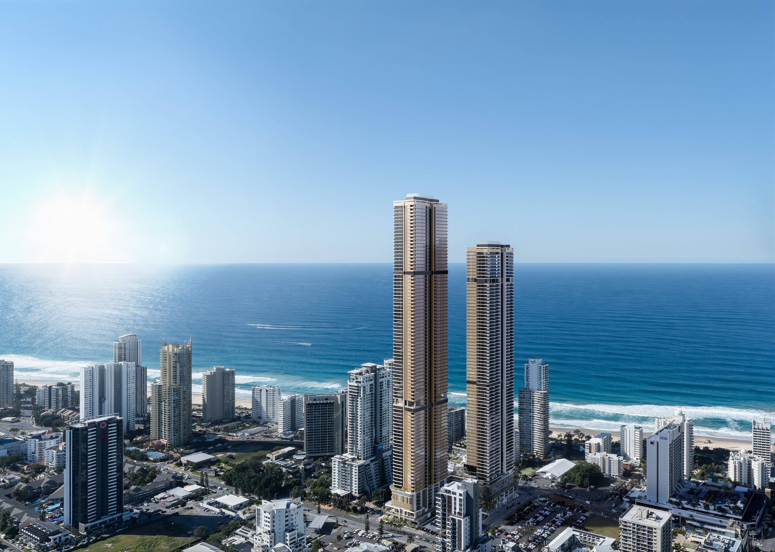 Aerial view of a Gold Coast, Australia with tall skyscrapers near the beach, with the ocean in the background under a clear blue sky.